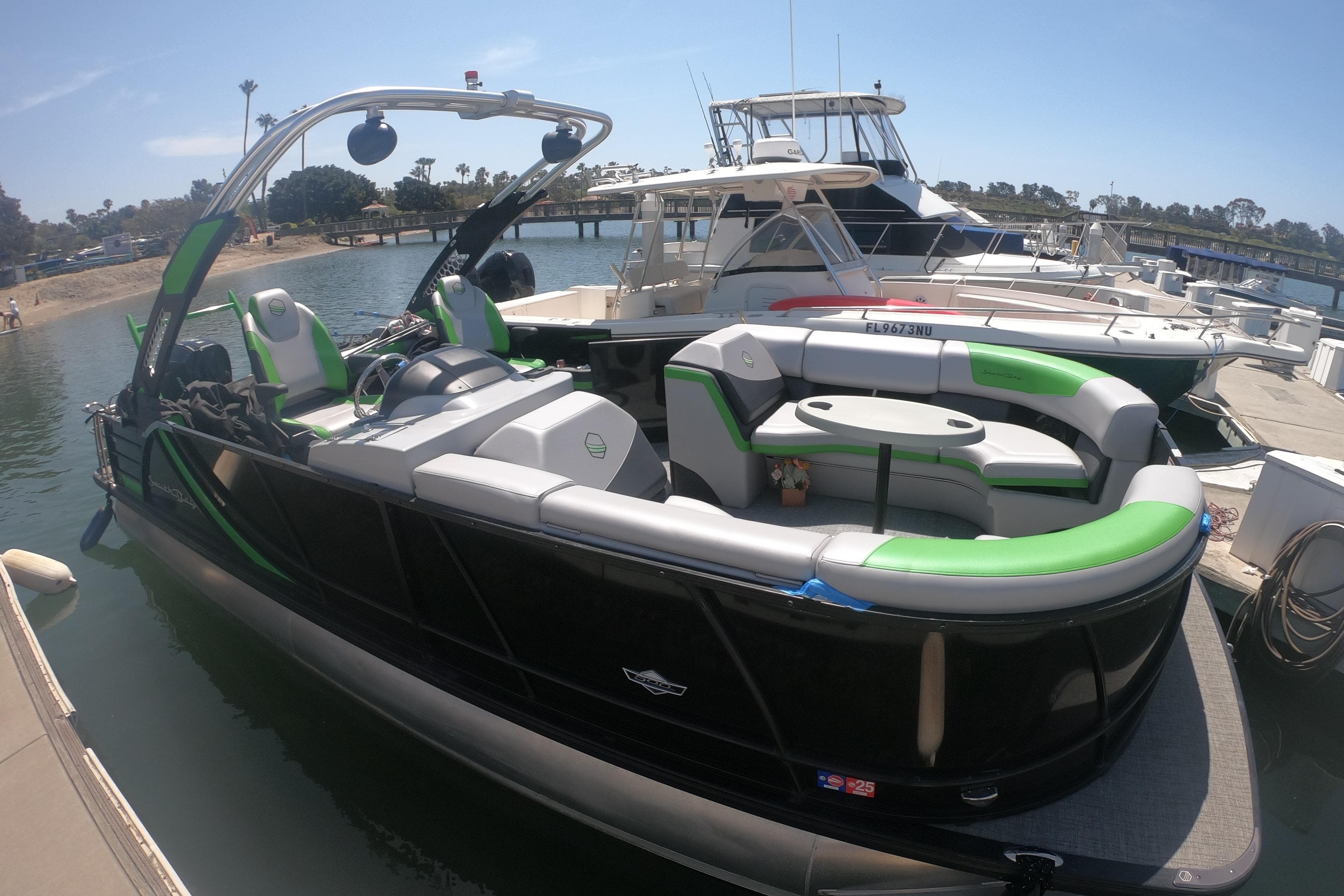 2023 South Bay 525UL AR pontoon boat docked, featuring sleek design and green accents.