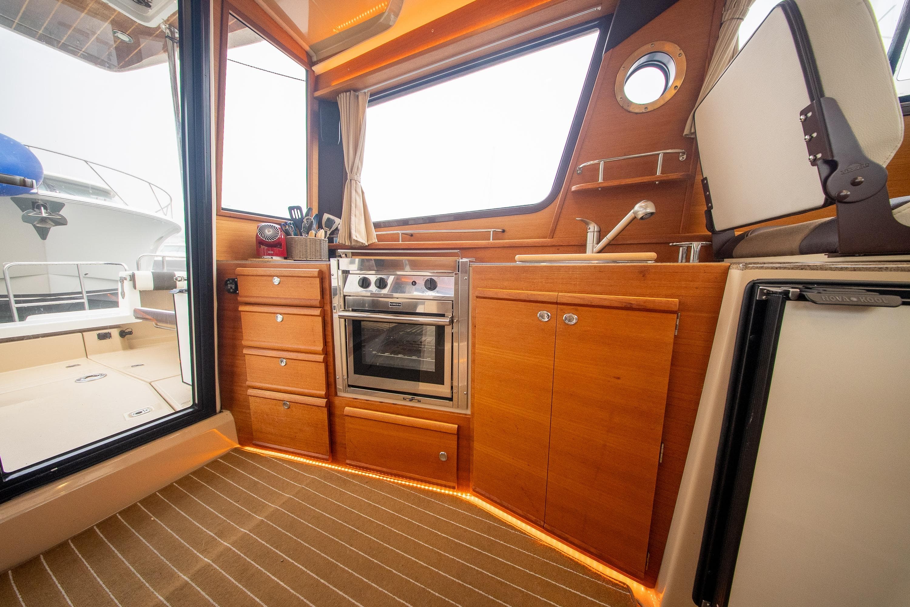 Interior of 2016 Ranger Tugs R-29, featuring a compact kitchen with wood cabinetry.