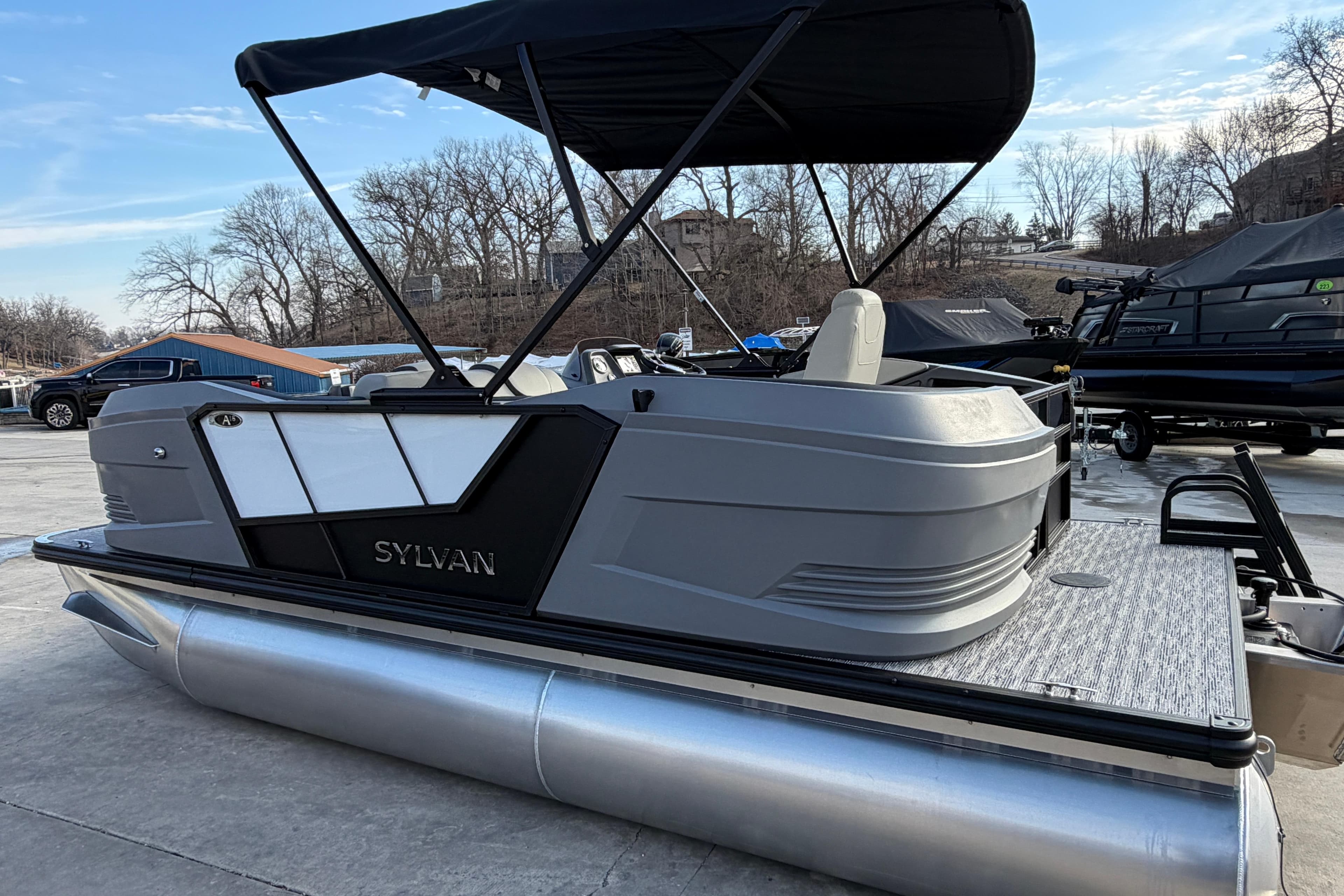 2026 Sylvan A-18 pontoon boat with canopy, docked outdoors on a sunny day.
