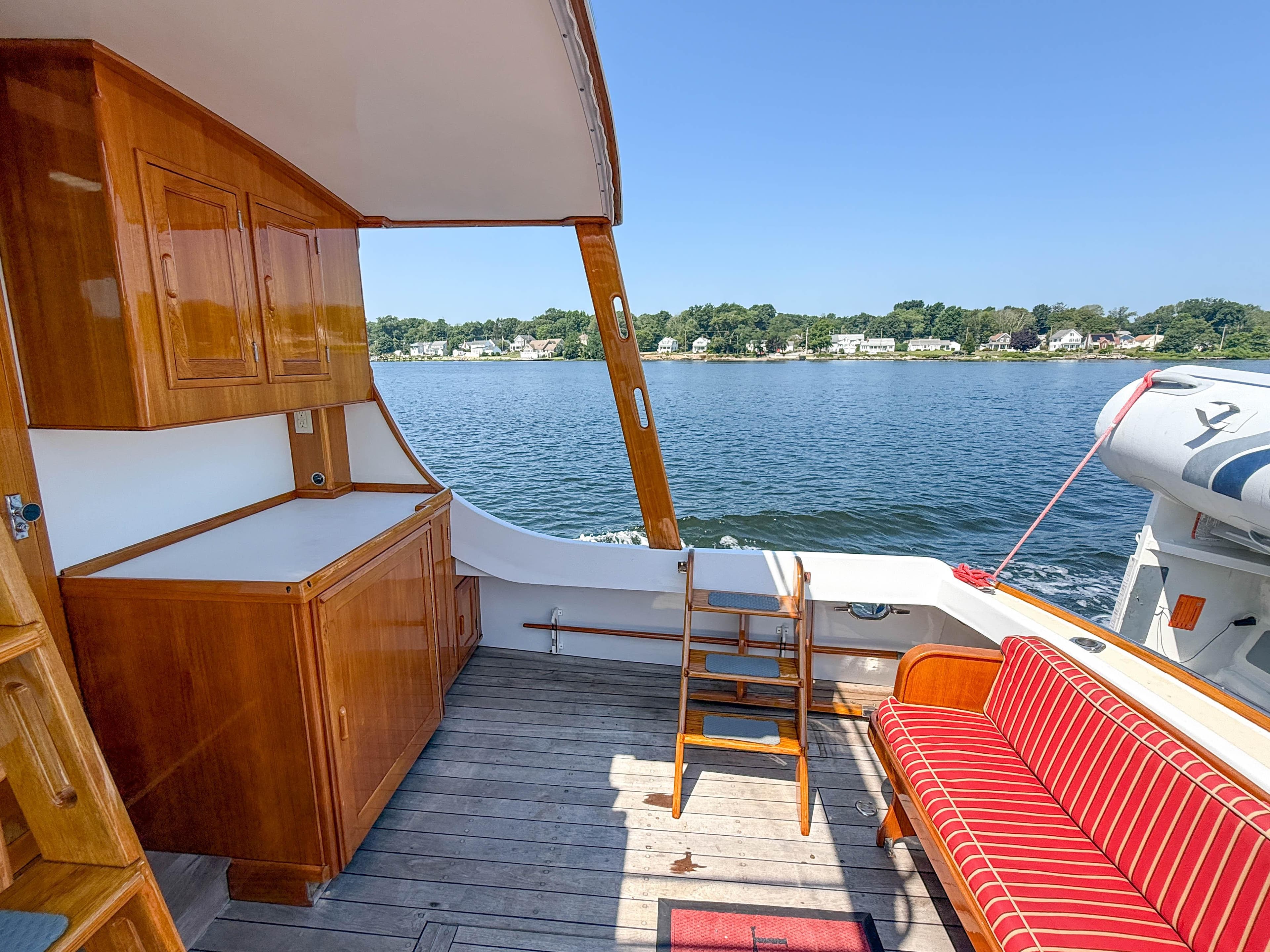 1984 Wilbur 38 boat interior with wooden cabinetry, striped seating, and scenic water view.