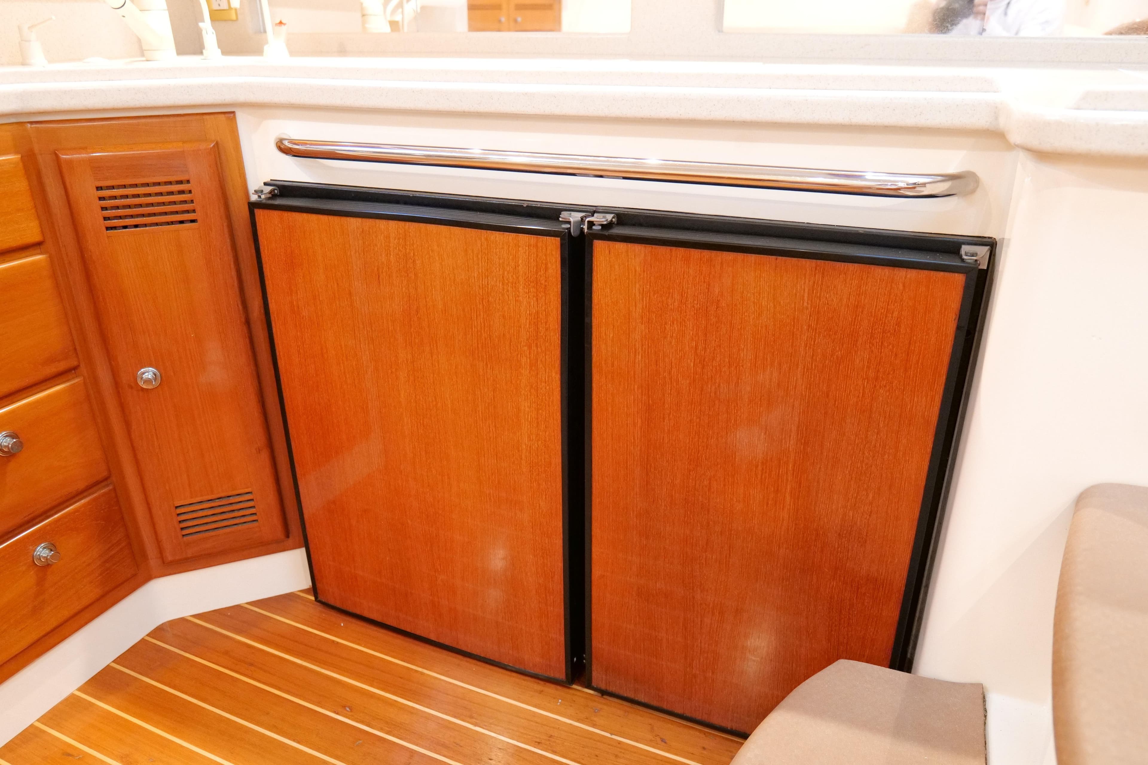 Wooden cabinetry and fridge in 1998 Cabo 45 Express yacht interior.