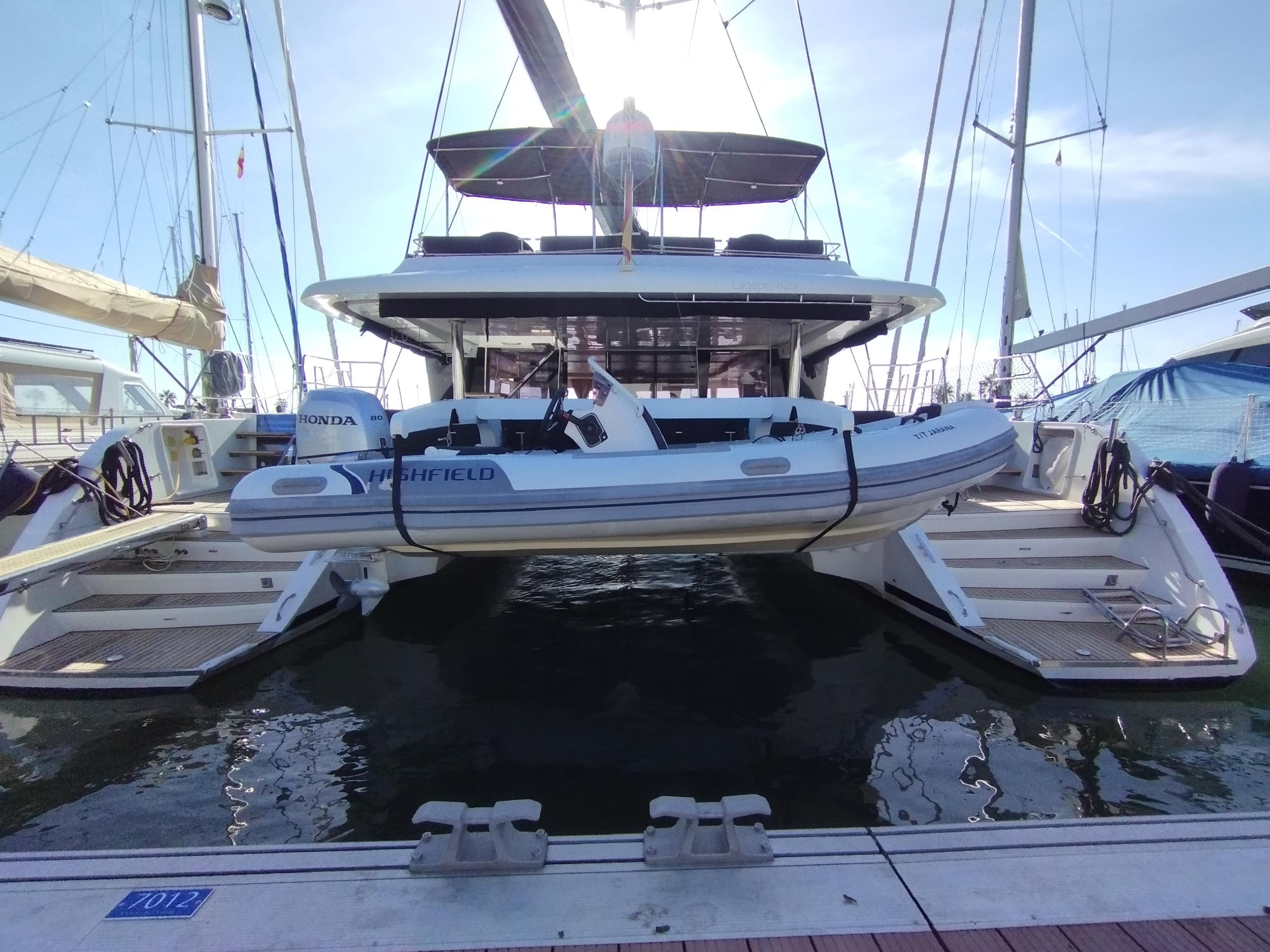 2012 Lagoon 620 catamaran with dinghy docked at marina, rear view.