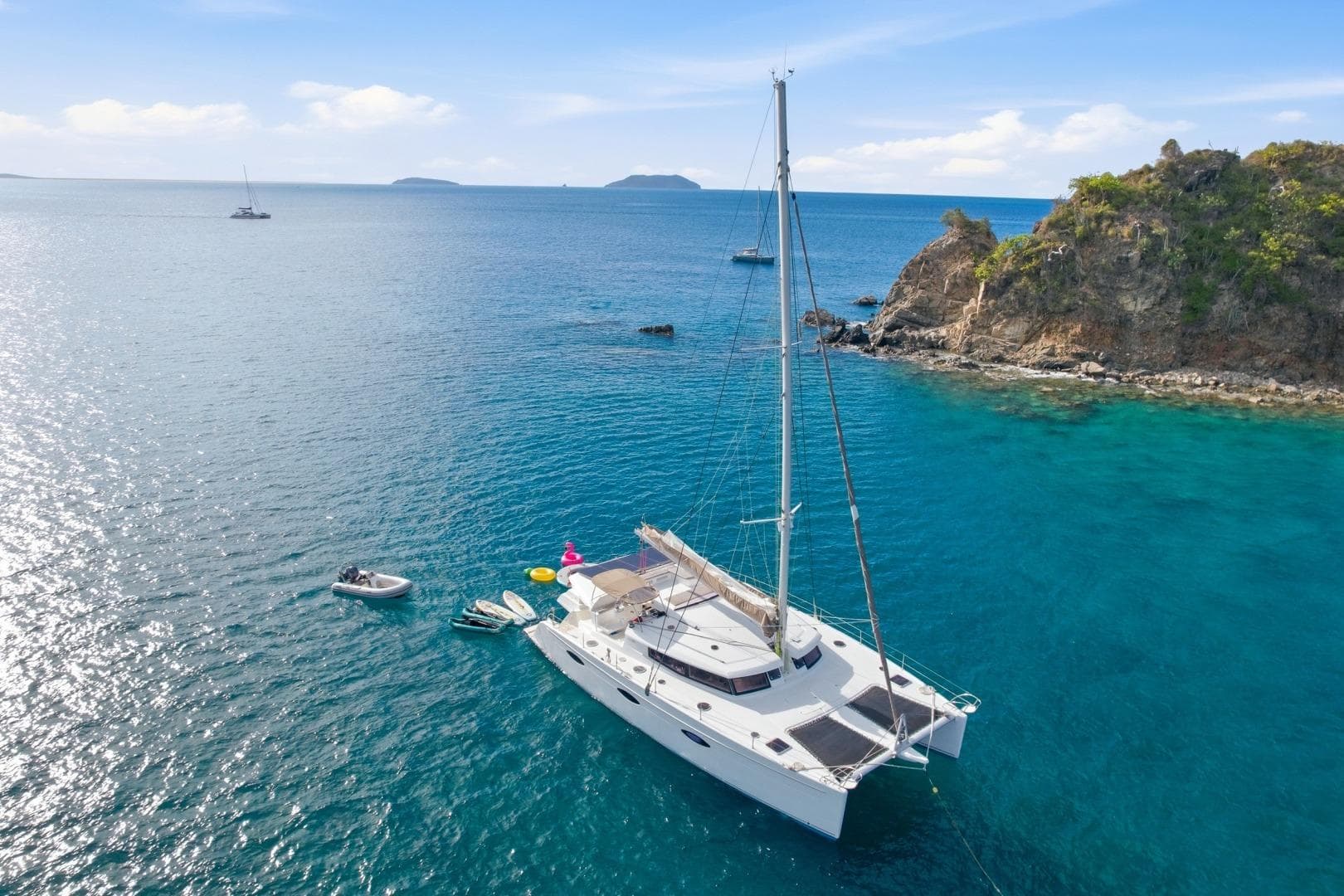 Fountaine Pajot Sanya 57 catamaran anchored in clear blue waters near rocky coastline, 2013 model.
