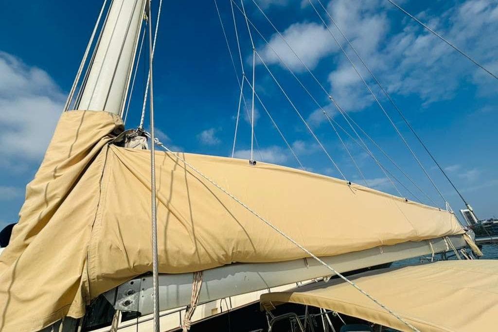 Sailboat mast and boom with beige cover under blue sky, Stevens 47, 1982 model.