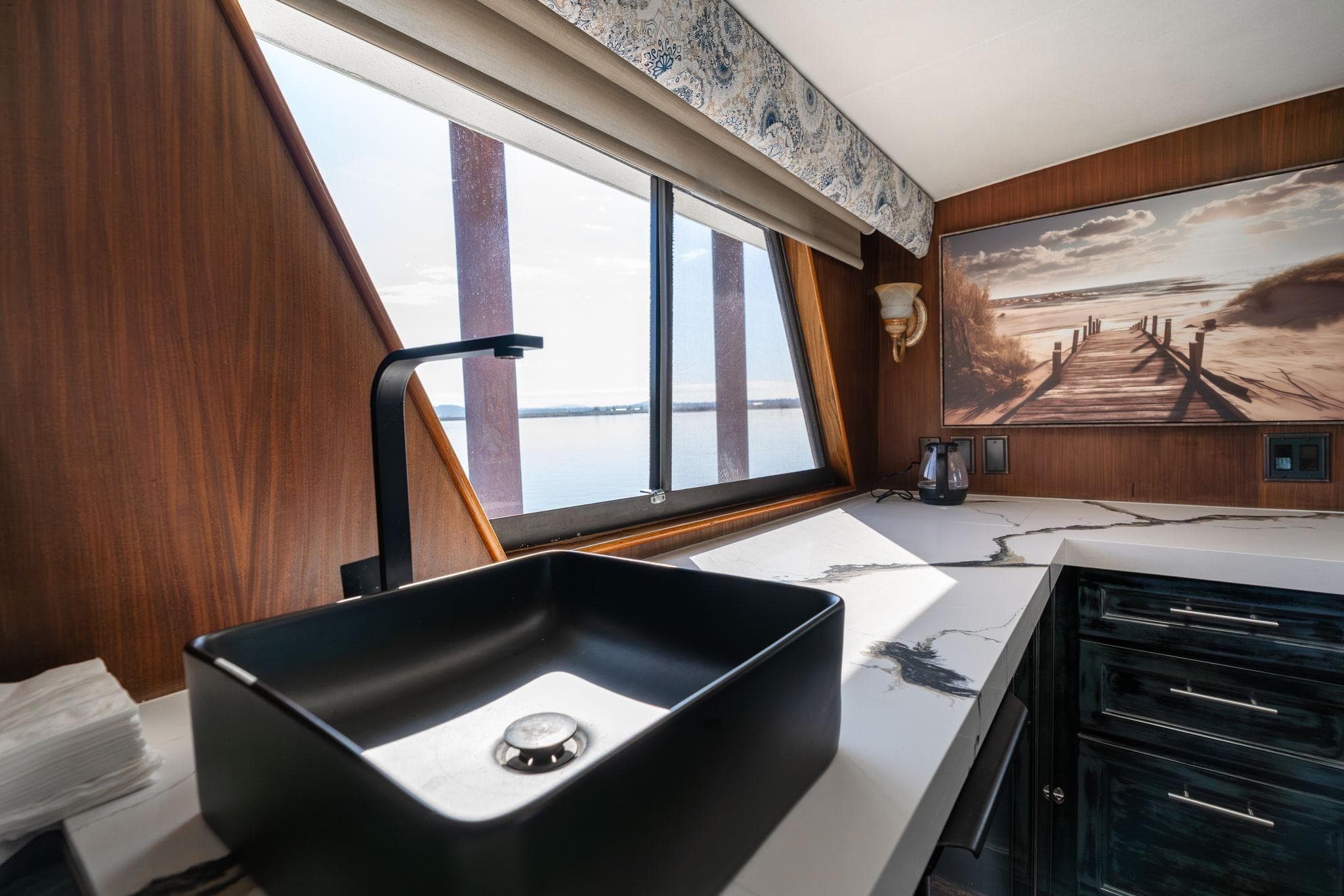 Luxurious kitchen interior of 1986 Hatteras 63 Motor Yacht with modern sink and scenic artwork.