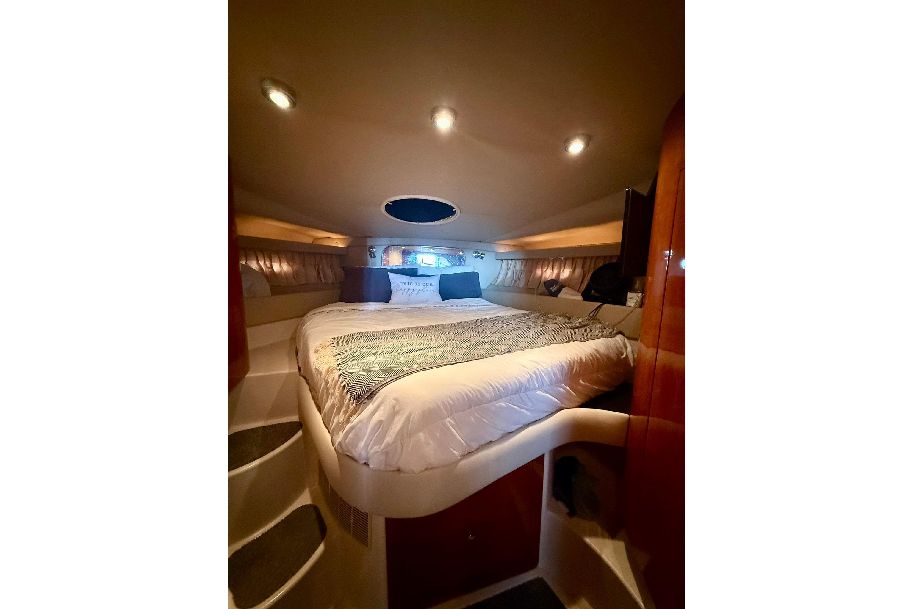 Luxurious cabin interior of 2006 Regal Commodore 4060 yacht with cozy bed and ambient lighting.