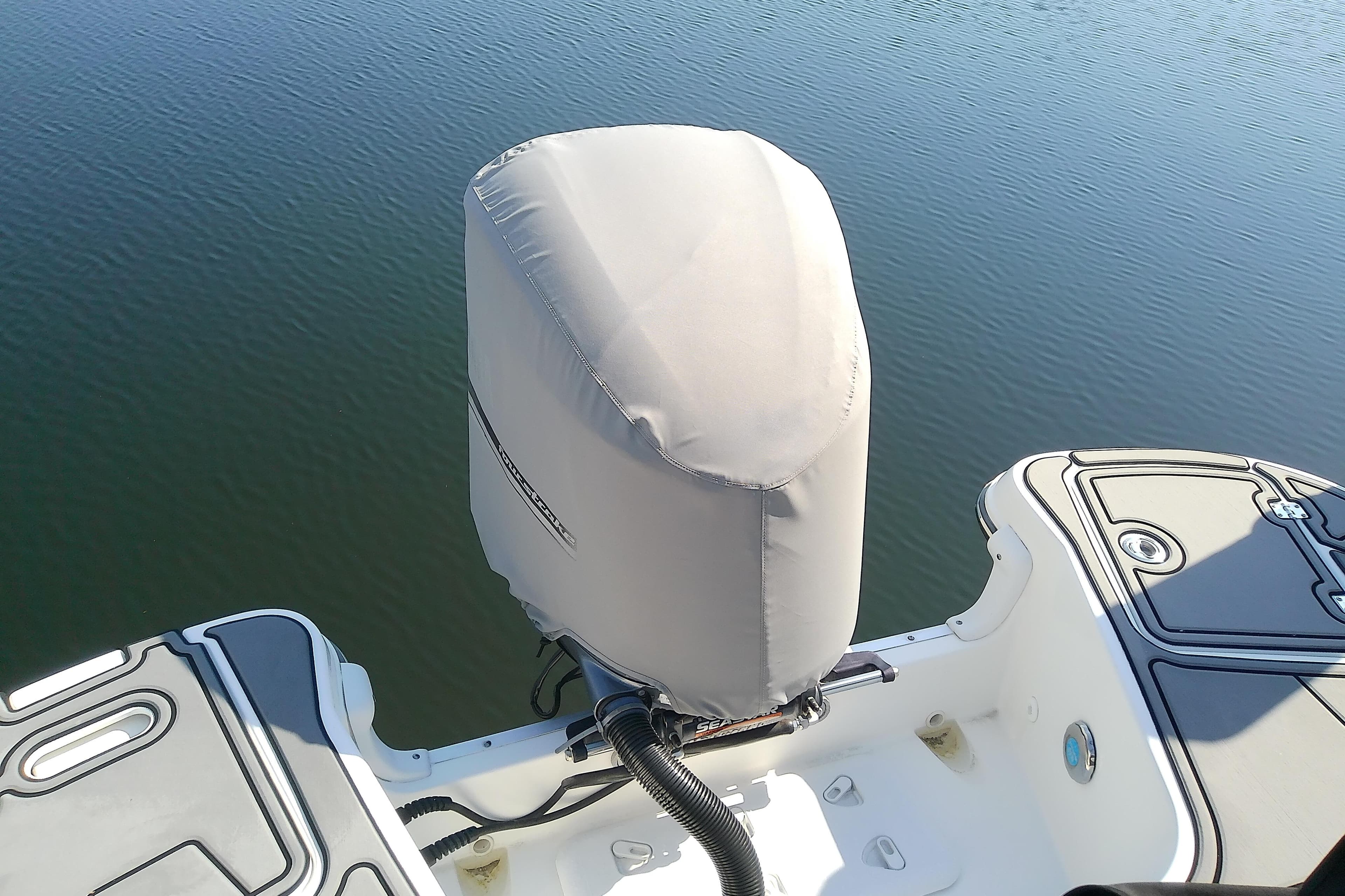 2021 Hurricane SunDeck 2410 OB boat engine covered, docked on calm water.