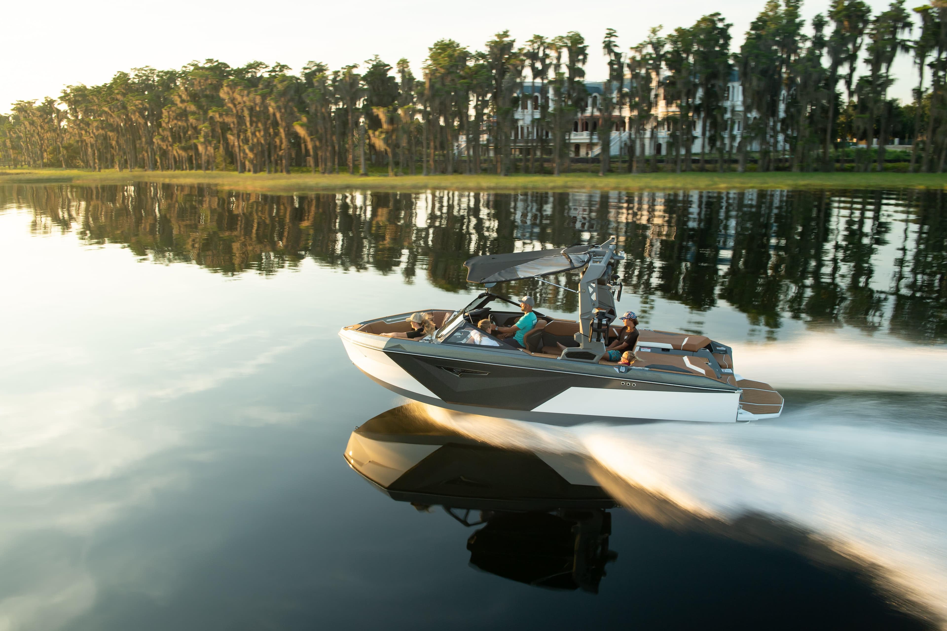 2026 Nautique S21 boat cruising on a calm lake with trees in the background.