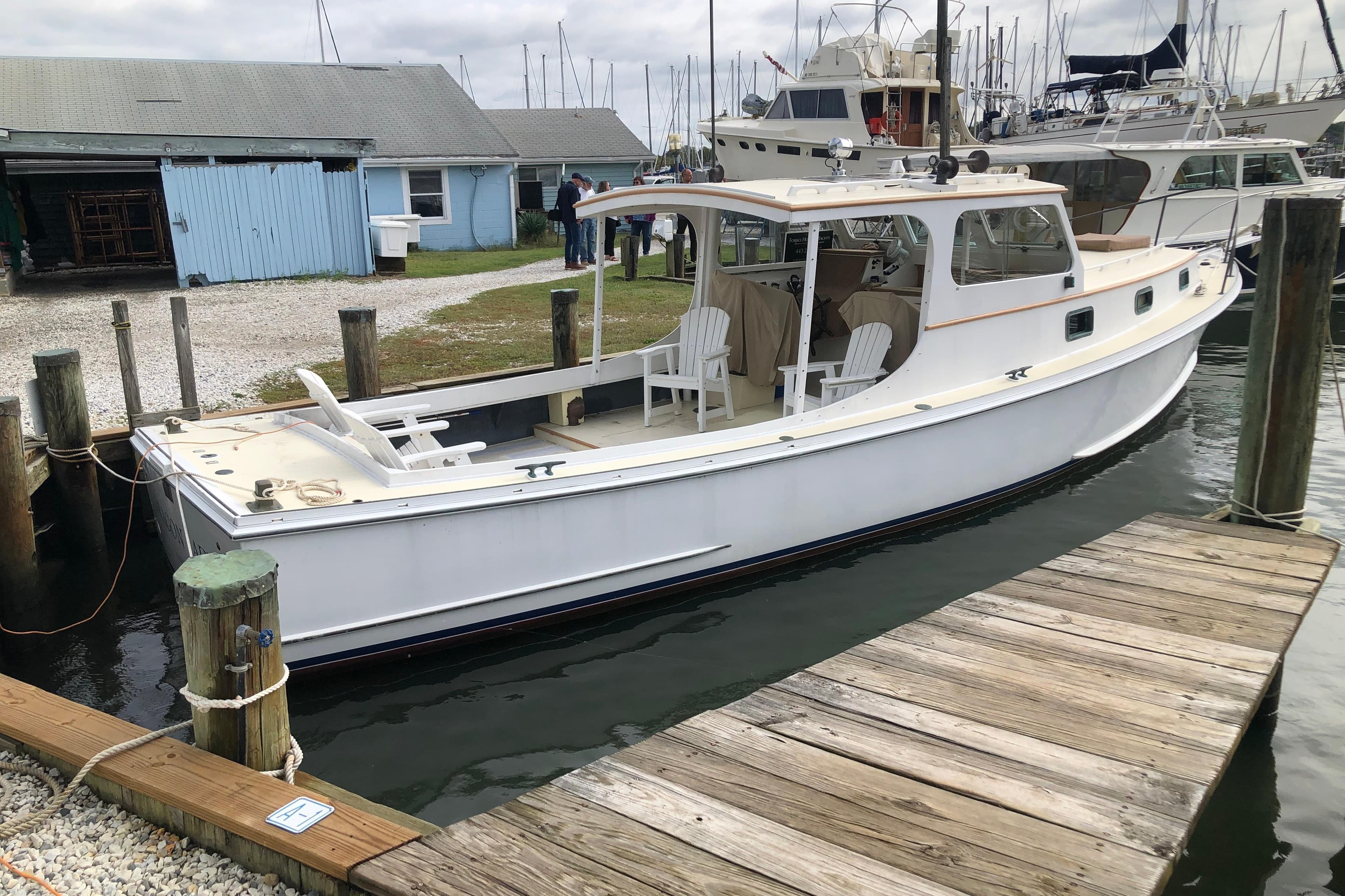 1972 Jarvis Newman Downeast boat docked at marina with wooden chairs on deck.