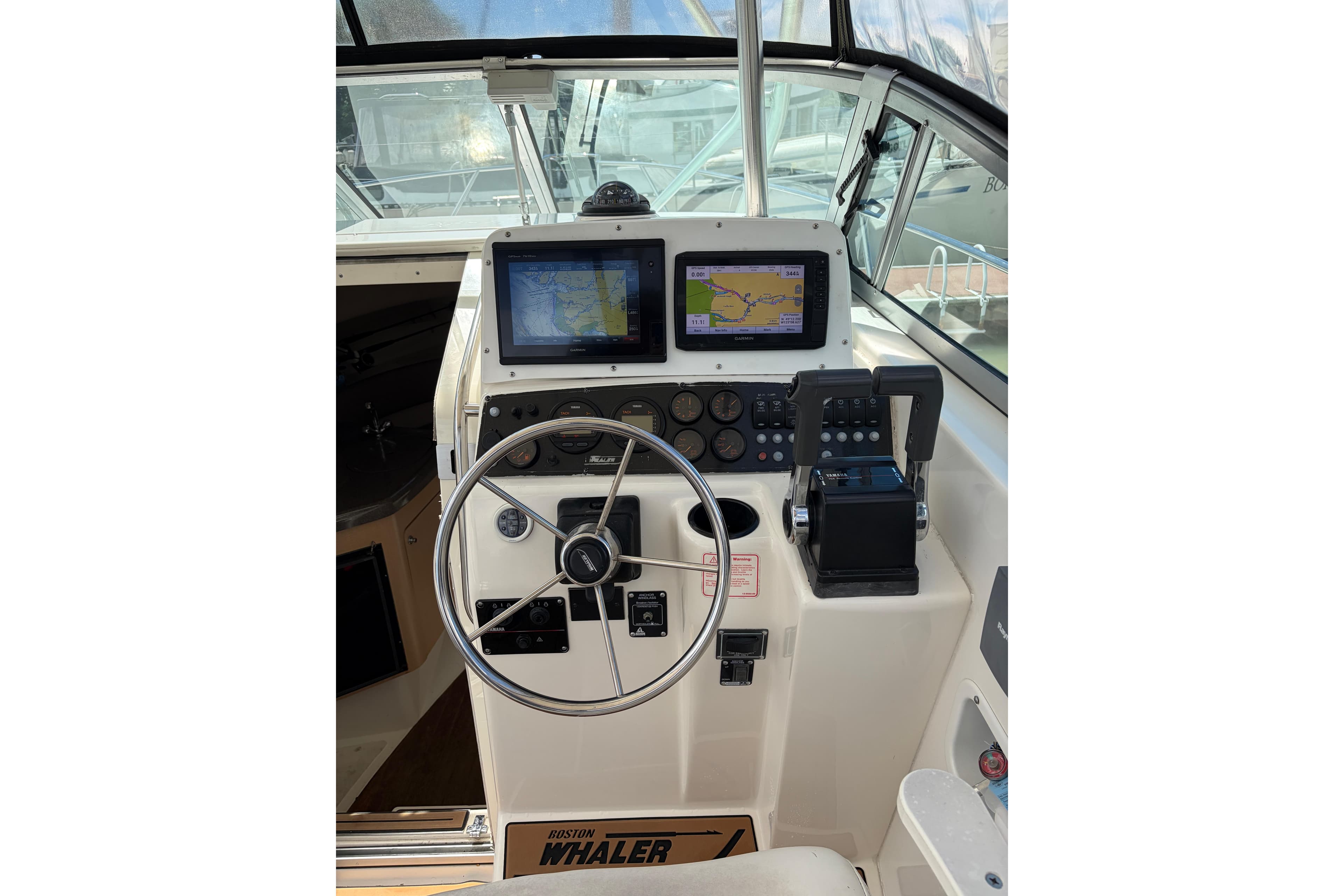 Helm of 1999 Boston Whaler 28 Conquest with navigation screens and steering wheel.