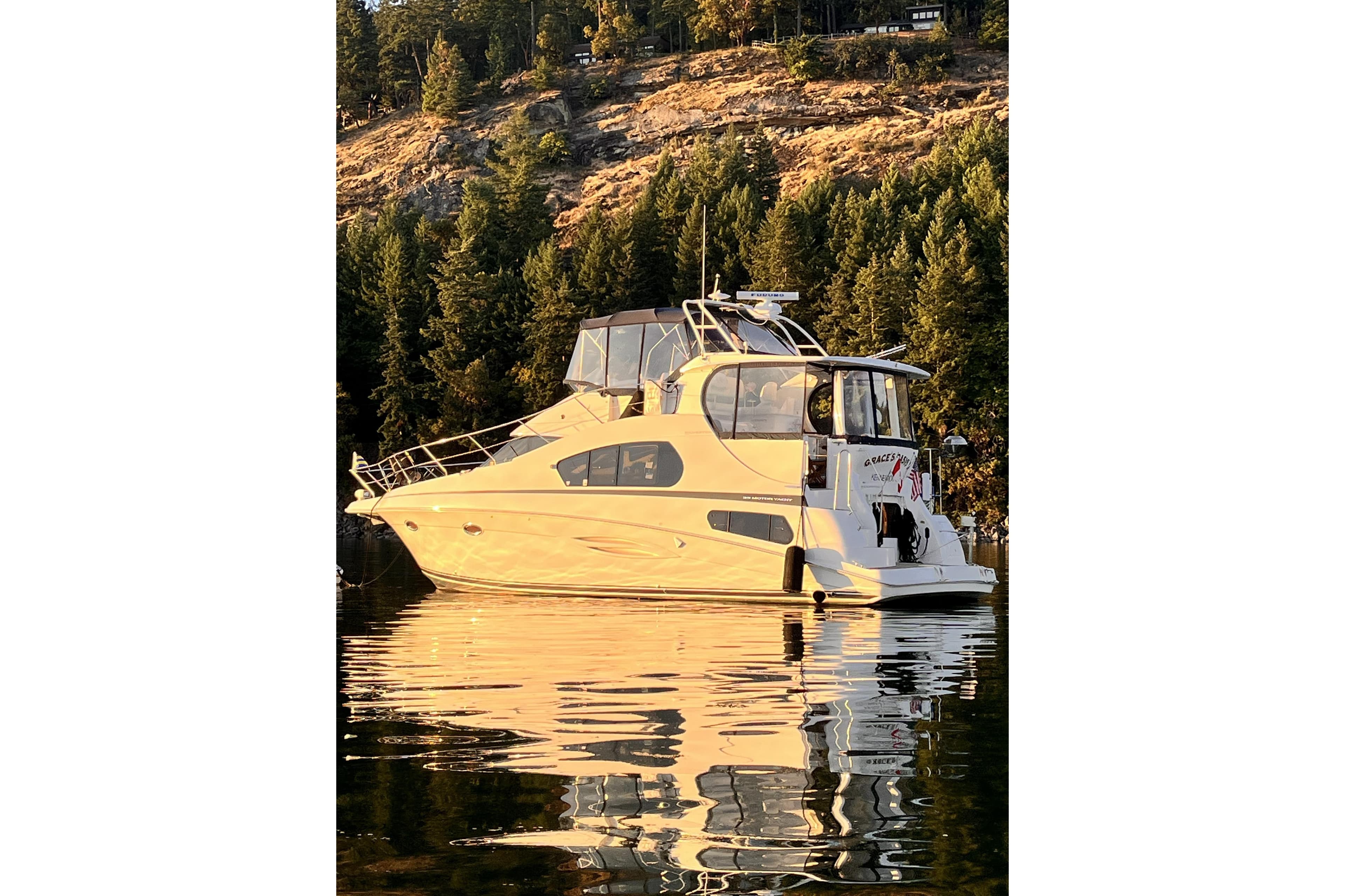 2005 Silverton 39 Motor Yacht on calm water, surrounded by forested hills.