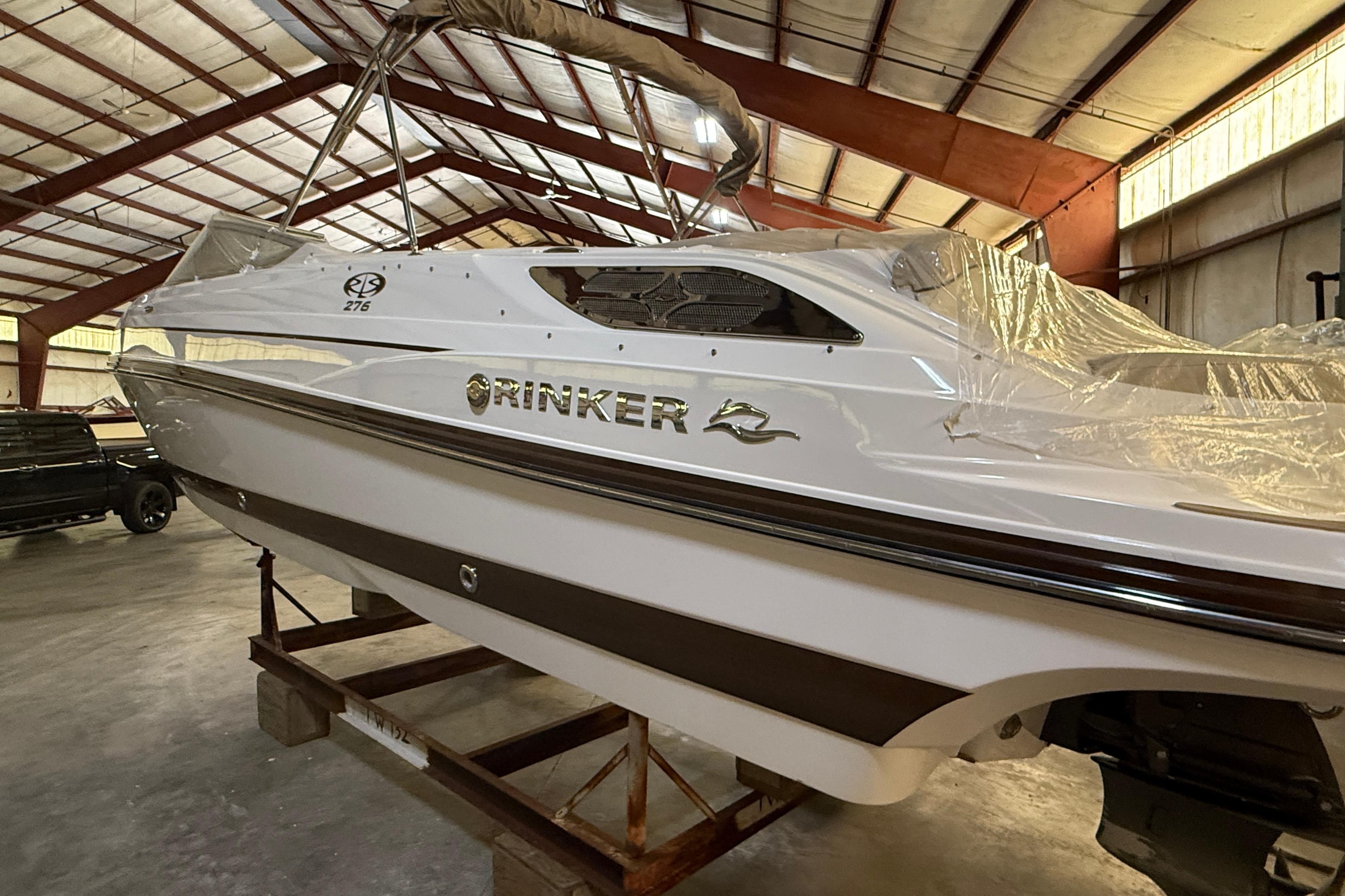 2013 Rinker 276 Captiva Bowrider boat in storage, partially covered, in a warehouse.