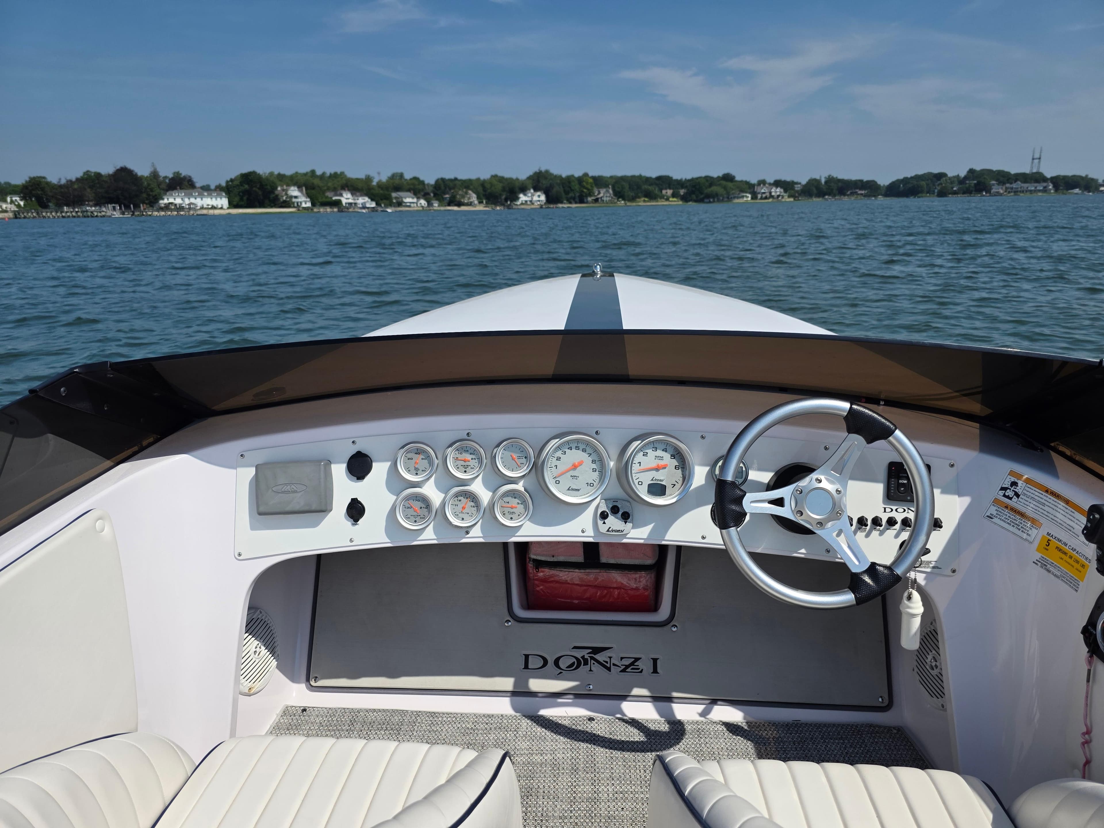 2018 Donzi 22 Classic boat dashboard with gauges and steering wheel on open water.
