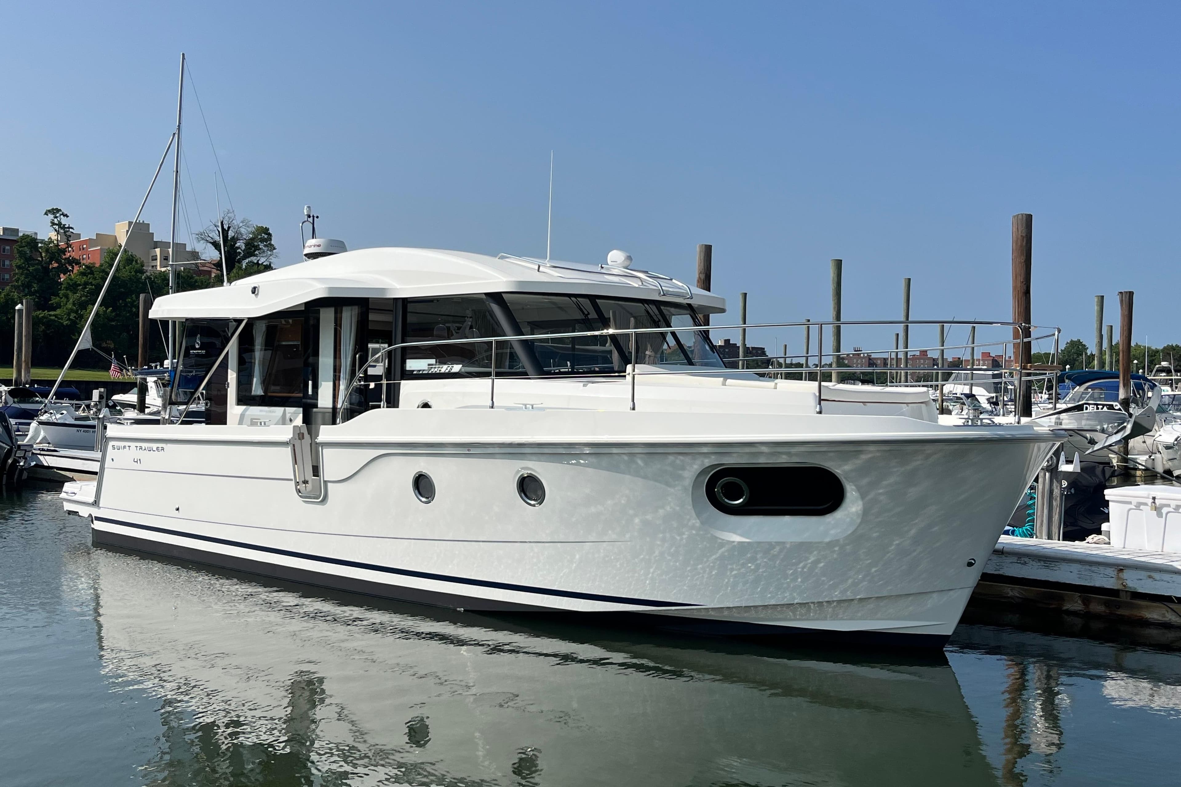2026 Beneteau 41 Swift Trawler Sedan docked at marina under clear blue sky.