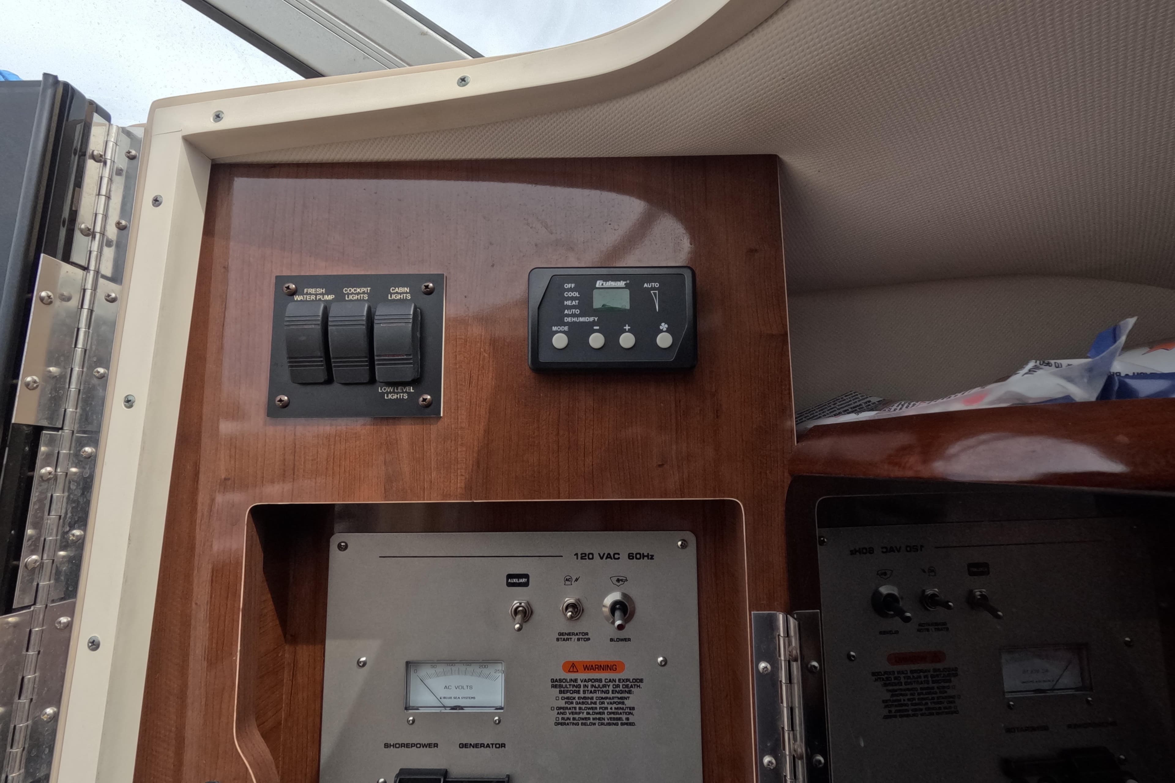 2012 Four Winns V265 control panel with switches and gauges on wooden interior.
