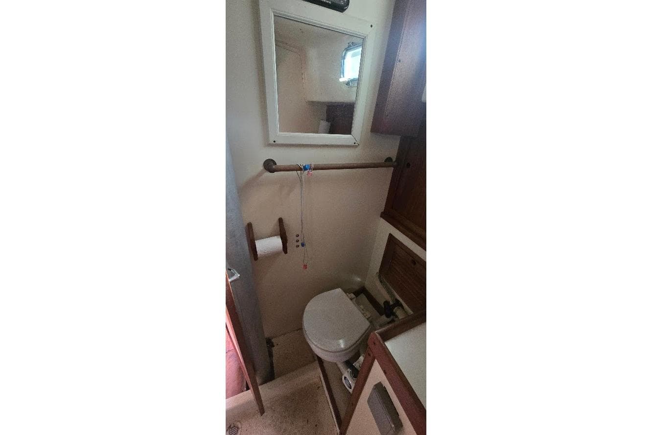 1978 Tartan T34c yacht bathroom with toilet, mirror, and wooden cabinets.