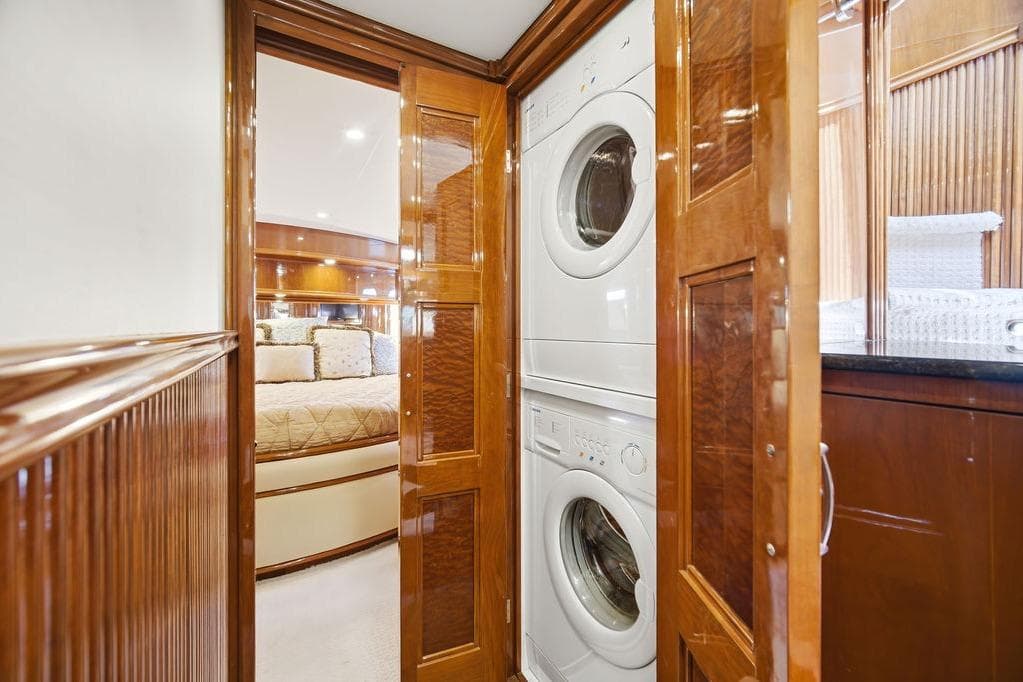 Luxurious 2006 Marquis 59 yacht interior with stacked washer and dryer in wooden cabinetry.