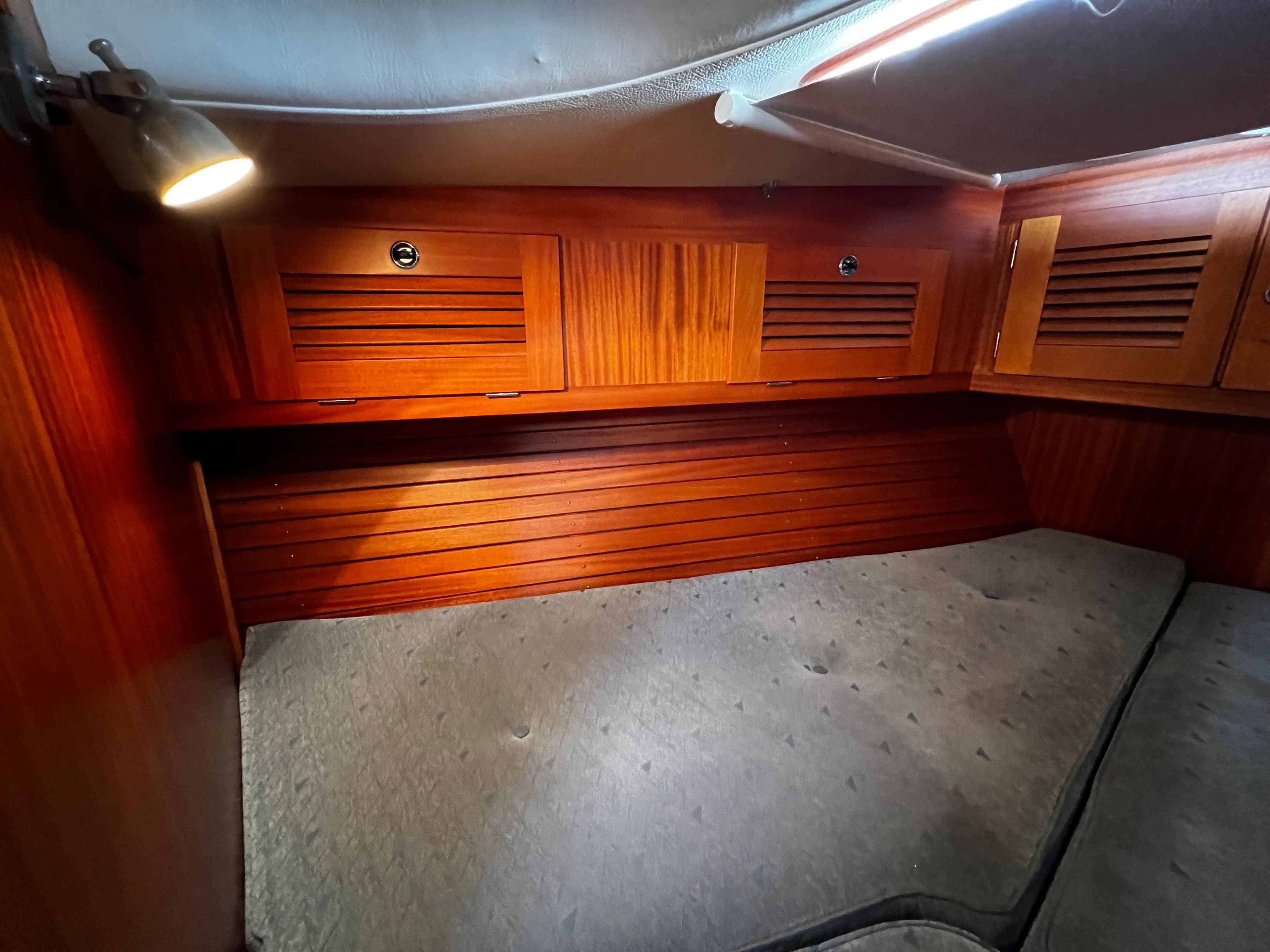 Cozy cabin interior of 2001 Hallberg-Rassy 42 sailboat with wooden paneling and soft lighting.
