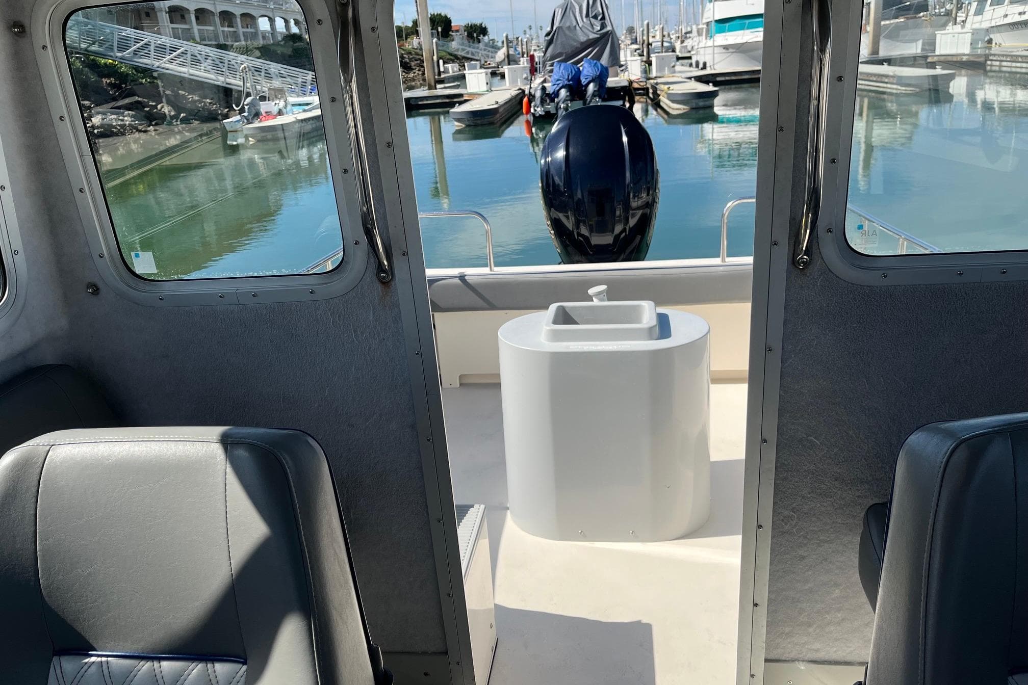 Interior view of 2023 Defiance Admiral 220 EX boat at marina, showcasing seating and engine.