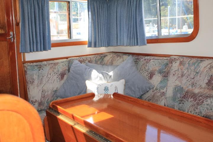 Cozy interior of 1989 Eagle Pilothouse with cushioned seating and wooden table.