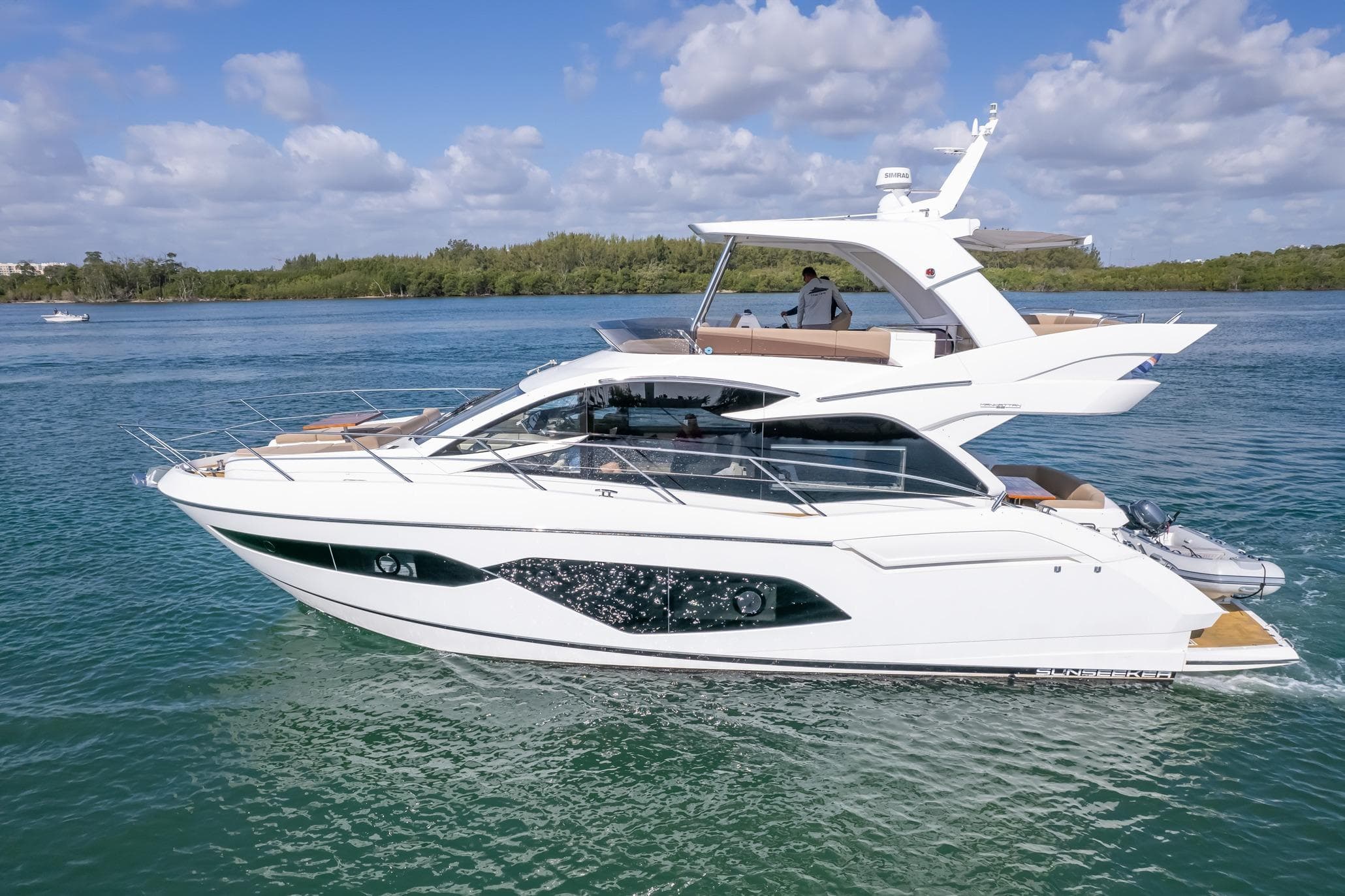 2018 Sunseeker Manhattan 52 yacht cruising on a serene blue waterway.