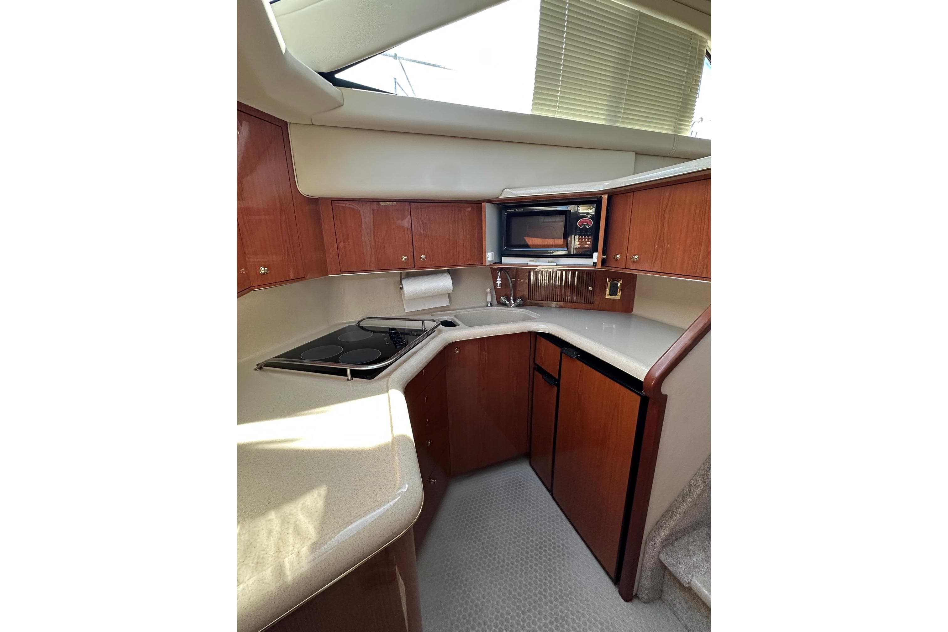 2000 Sea Ray 380 Aft Cabin kitchen with wood cabinets, microwave, and compact appliances.