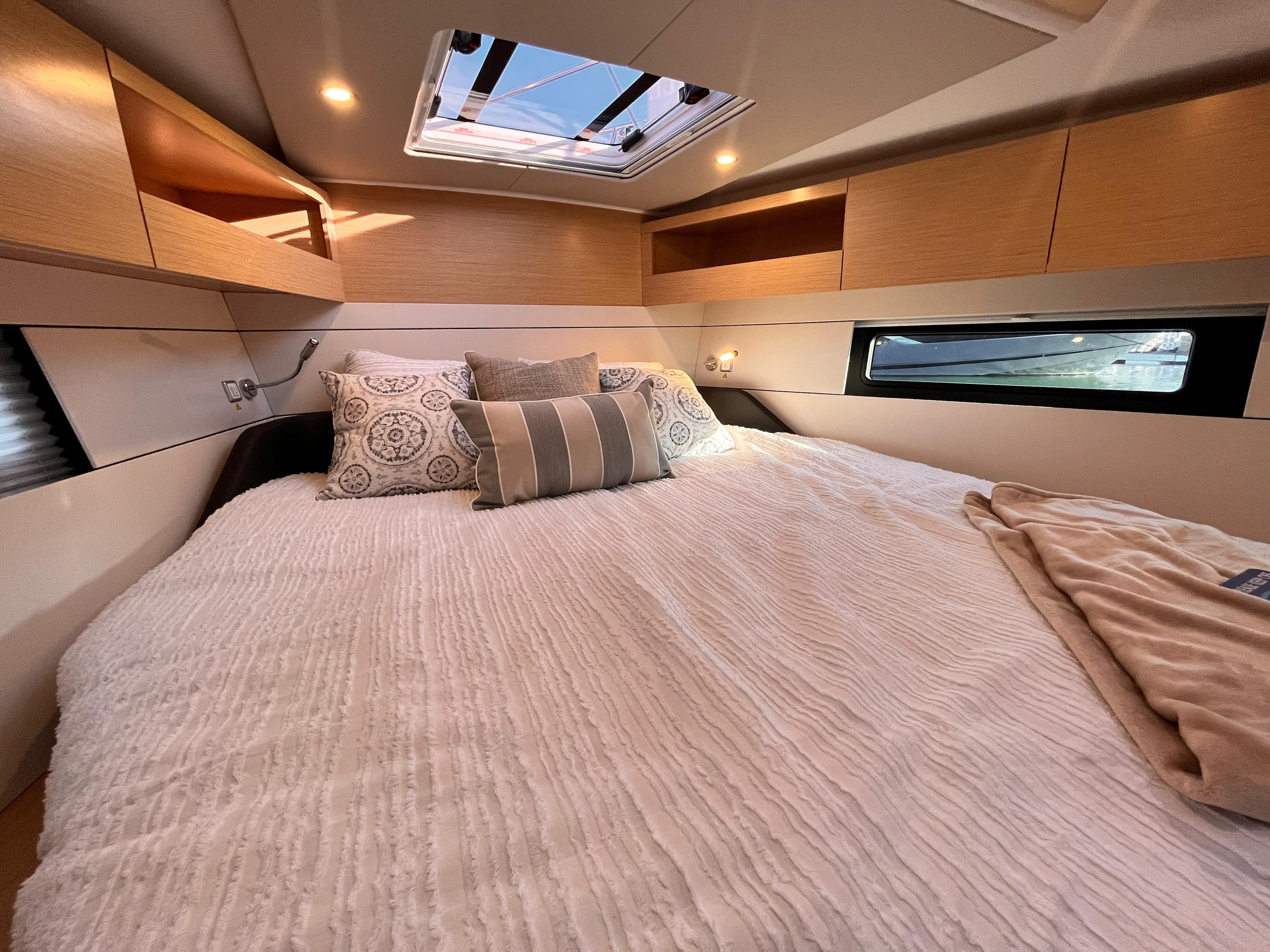 Luxurious cabin interior of 2023 Hanse 460 yacht with skylight and cozy bedding.