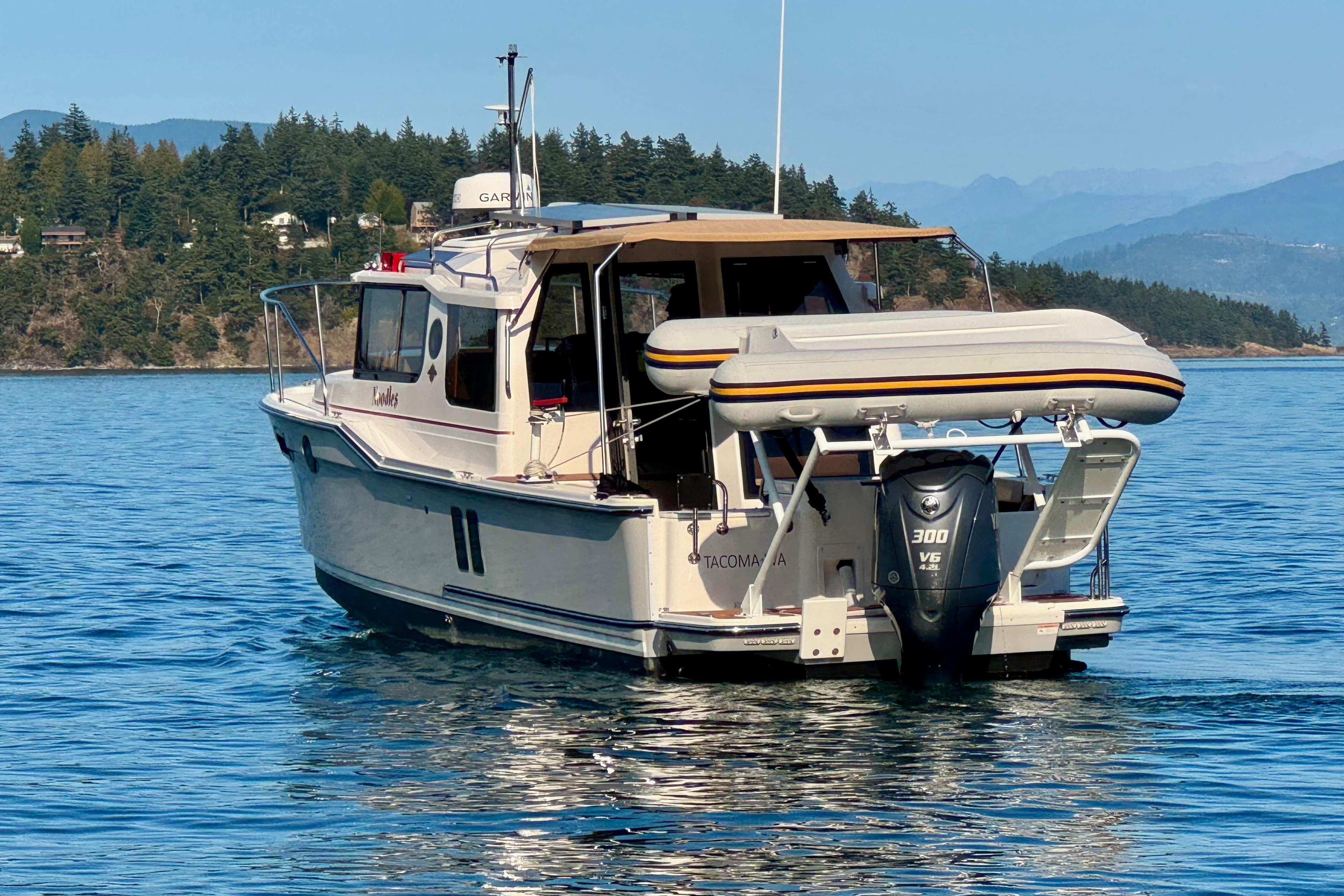 2024 Ranger Tugs R-27 boat on calm water with scenic forested background.