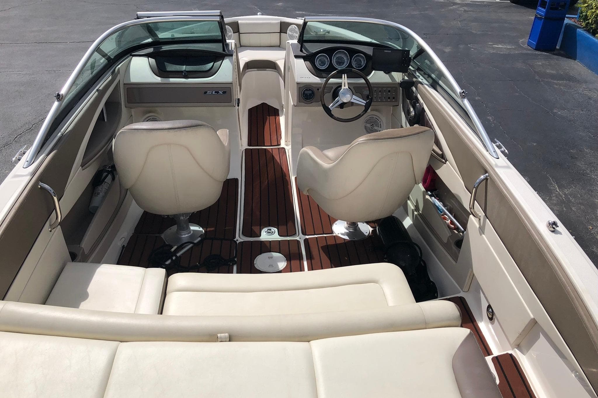 Interior view of a 2012 Sea Ray 210 SLX boat with beige seating and wooden flooring.