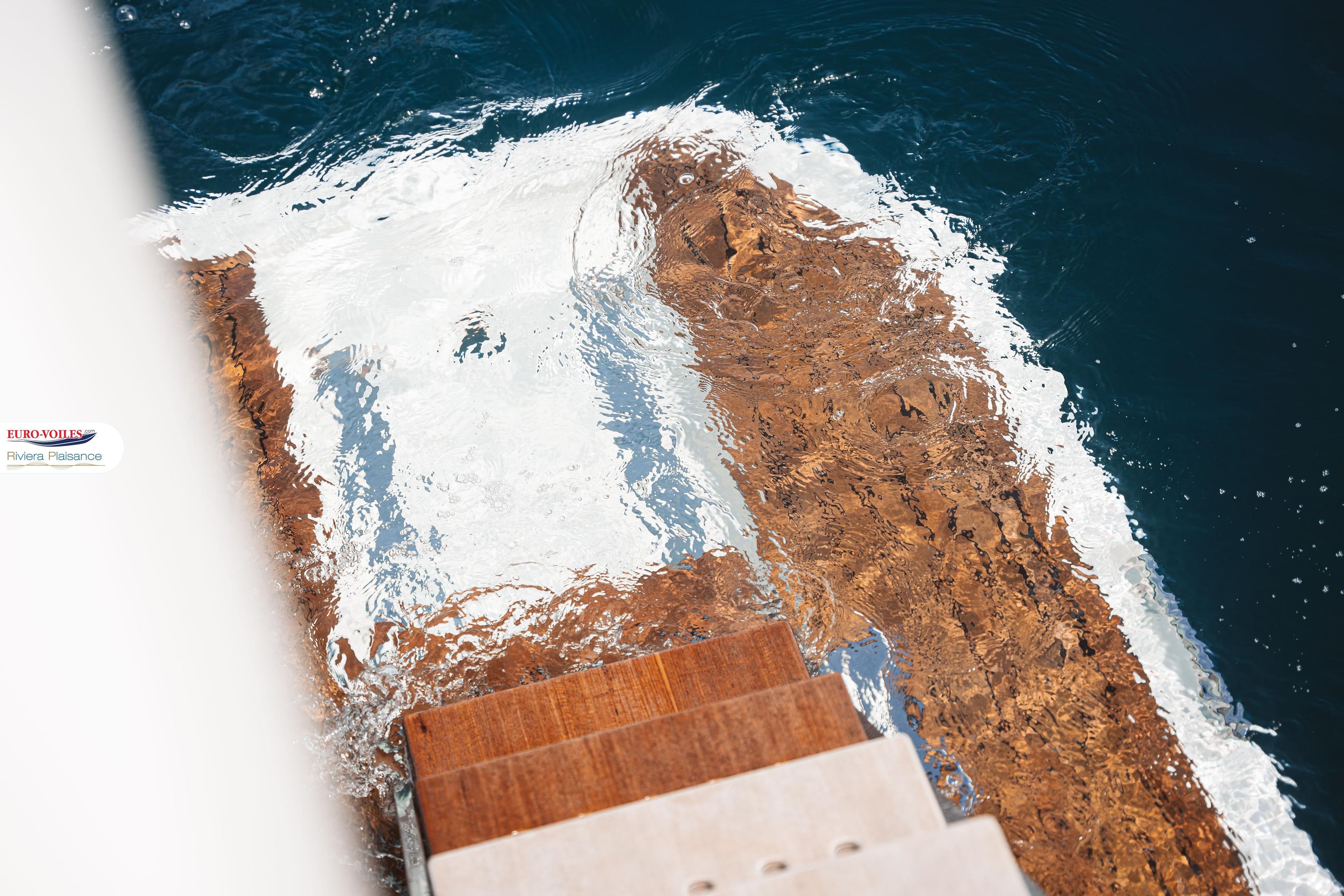 Wooden yacht steps of 2021 Prestige 590 Fly, reflecting in clear water.