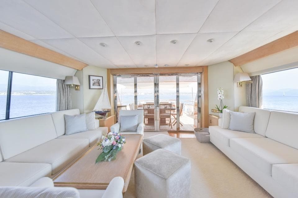 Luxurious yacht interior with elegant seating, floral centerpiece, and ocean view, W.A. Souter & Sons 1984.