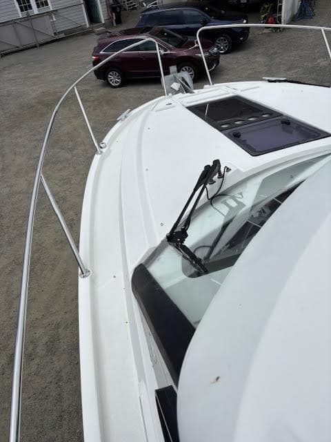 2019 Beneteau Antares 27 boat deck with windshield, parked cars in background.