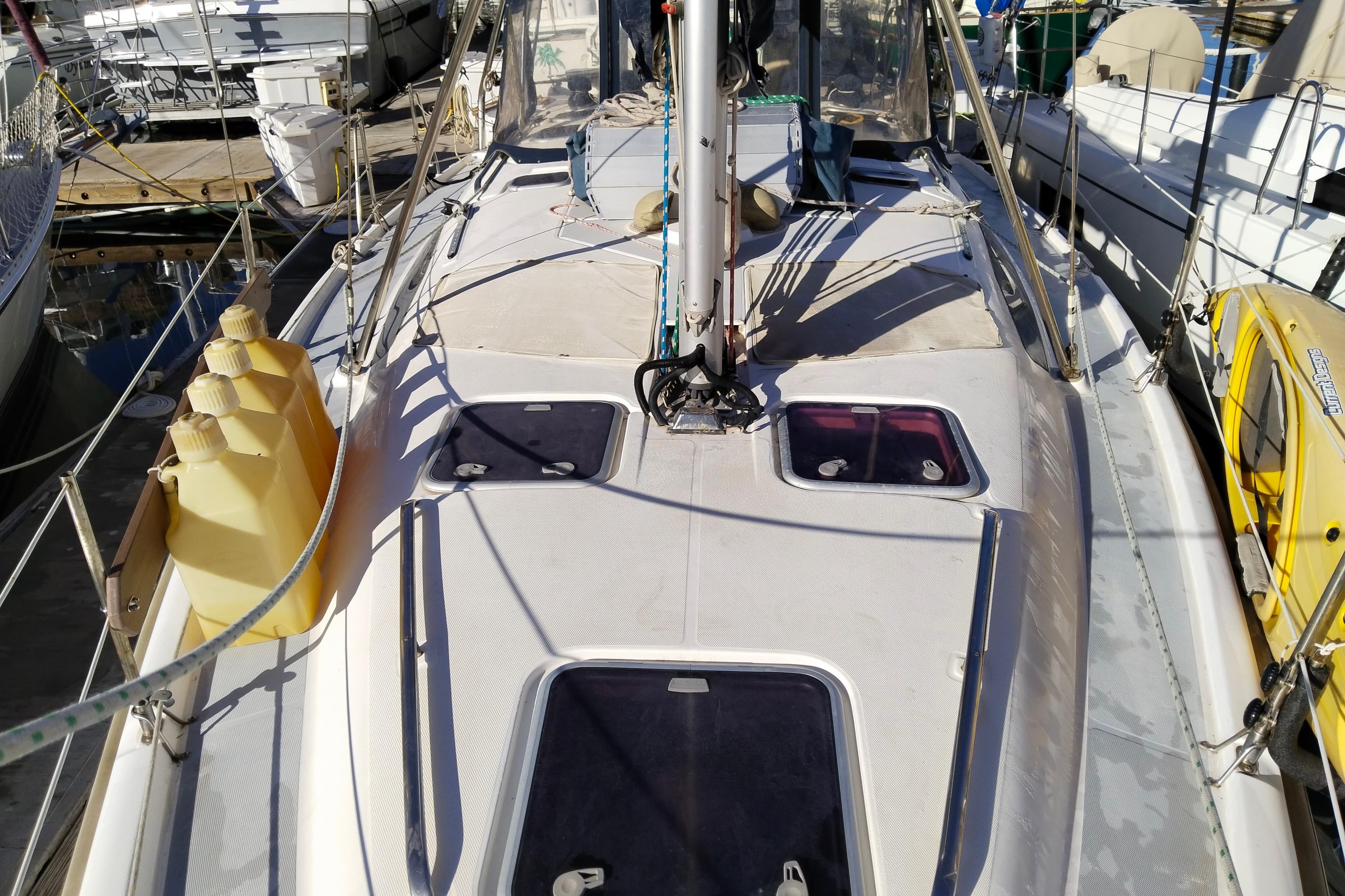 Sailboat deck of 1999 Hunter 380 with yellow fuel containers docked at marina.