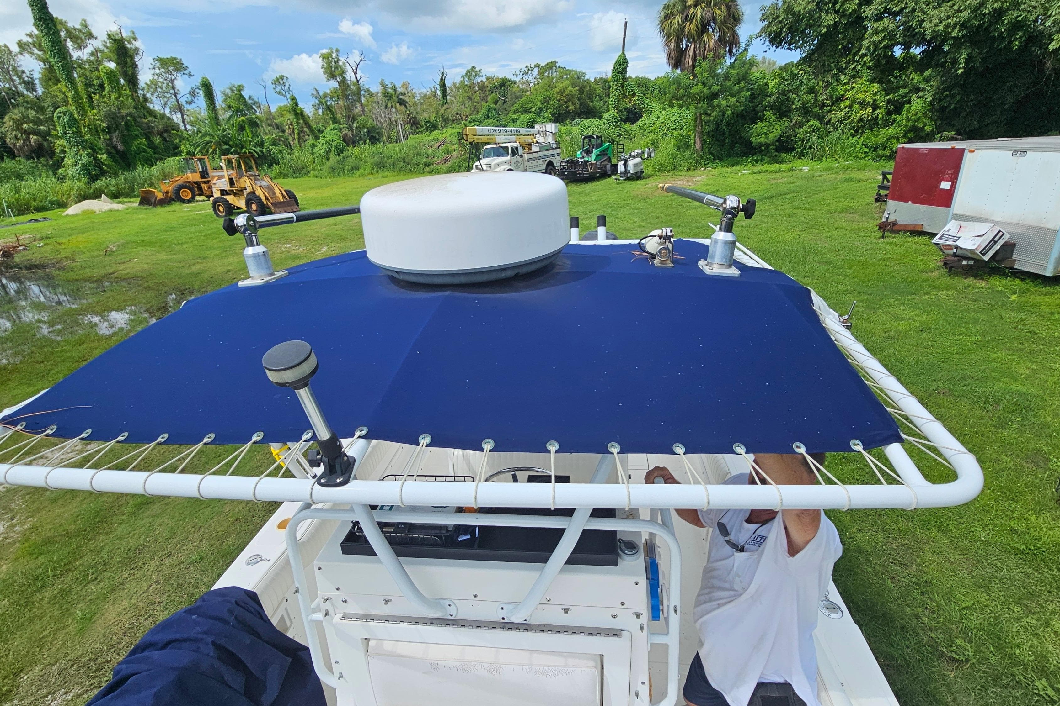 1993 Marlin 350 Sportfish boat with blue canopy, parked on grassy area.