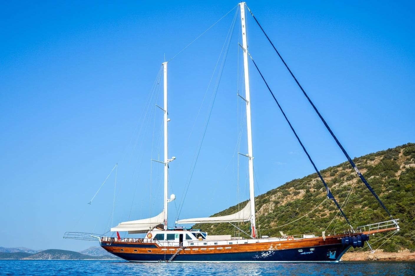 2007 Mastori Gulet sailing yacht anchored near a scenic hillside under a clear blue sky.