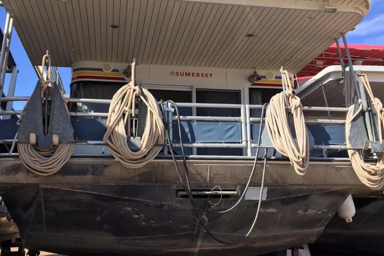 2005 Sumerset Star Chaser houseboat with ropes and anchors, docked under a clear sky.
