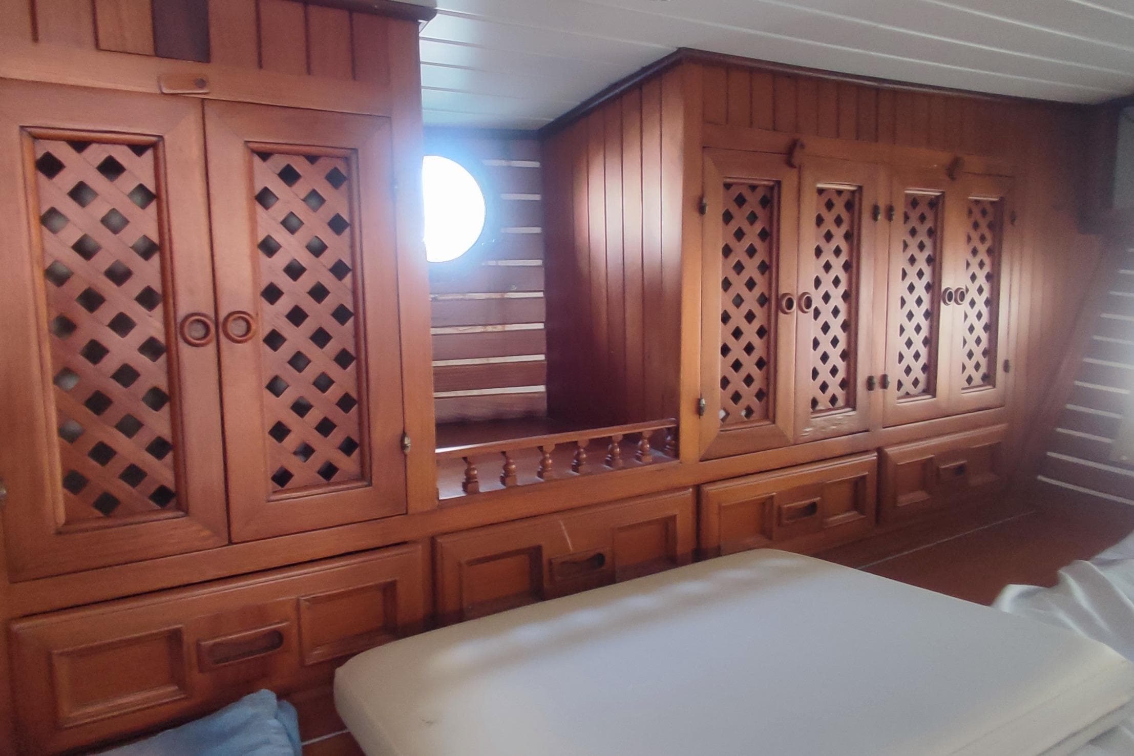 Wooden interior of 1980 Formosa 51 yacht with lattice cabinets and porthole window.