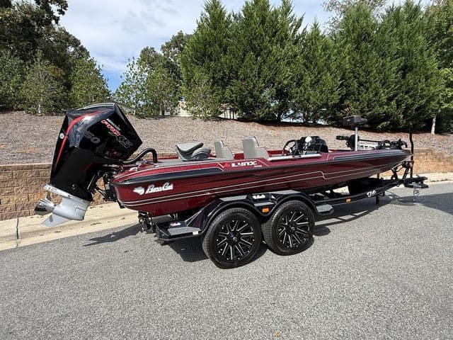 2026 Bass Cat Lynx STS boat with trailer, parked on a road, surrounded by trees.