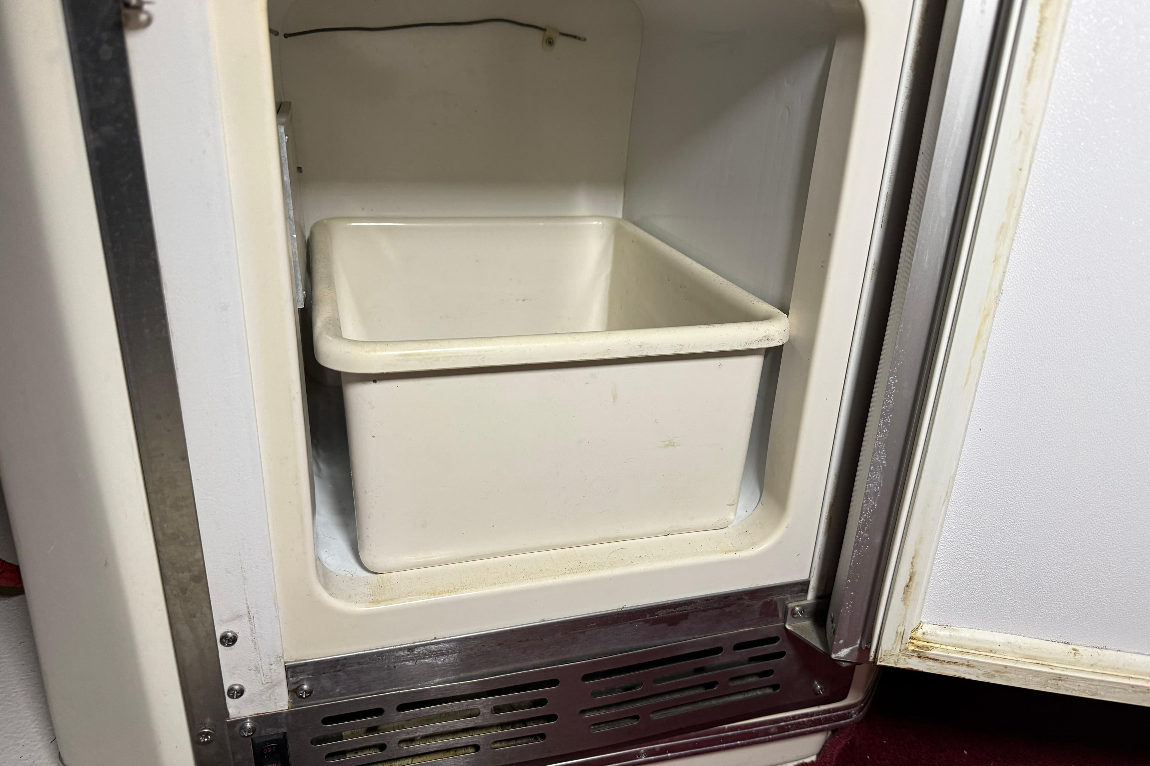 Open refrigerator compartment on 1989 Sea Ray 340 Express Cruiser, featuring a white storage bin.