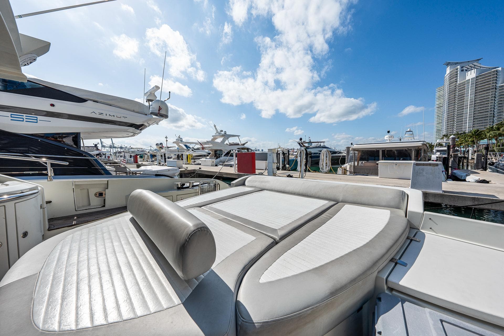 2007 Azimut 62S yacht at marina with luxurious seating, clear skies, and cityscape backdrop.