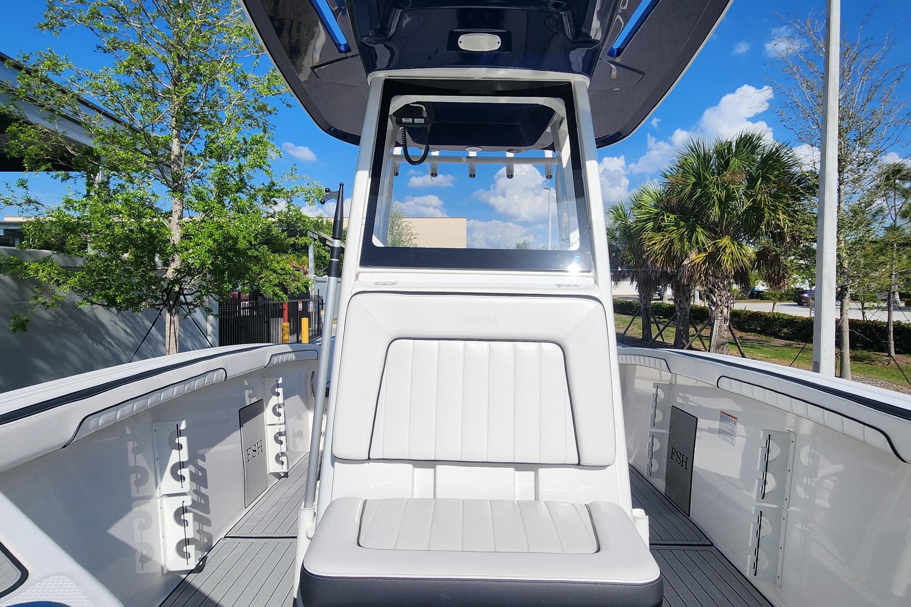 2022 Yamaha 255 FSH Sport E boat interior with seating and console, under a clear blue sky.