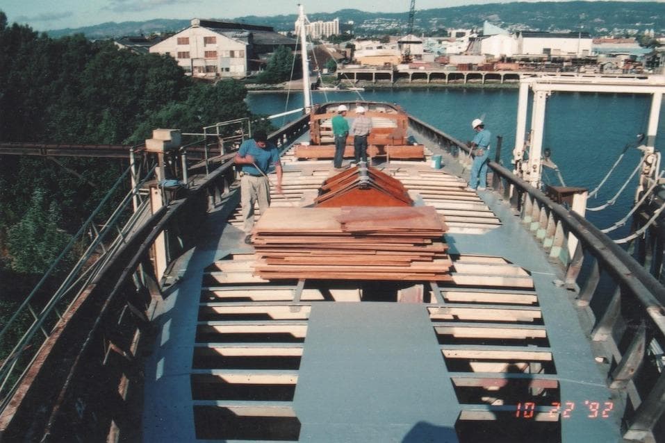 Workers on 1939 William McMeek Brooks Marine ship deck under construction, near waterfront.