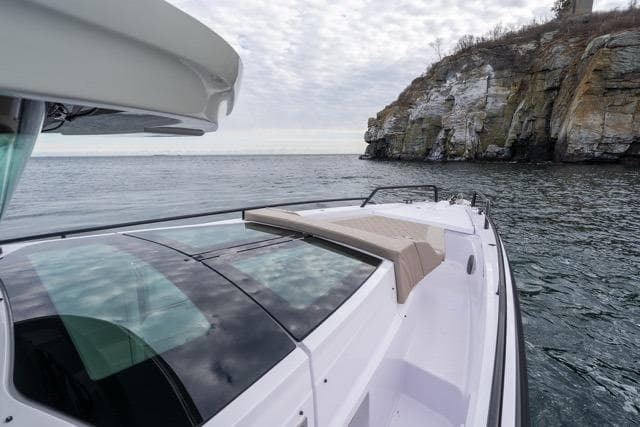 2026 Axopar 37 XC Cross Cabin cruising near rocky coastline under cloudy sky.