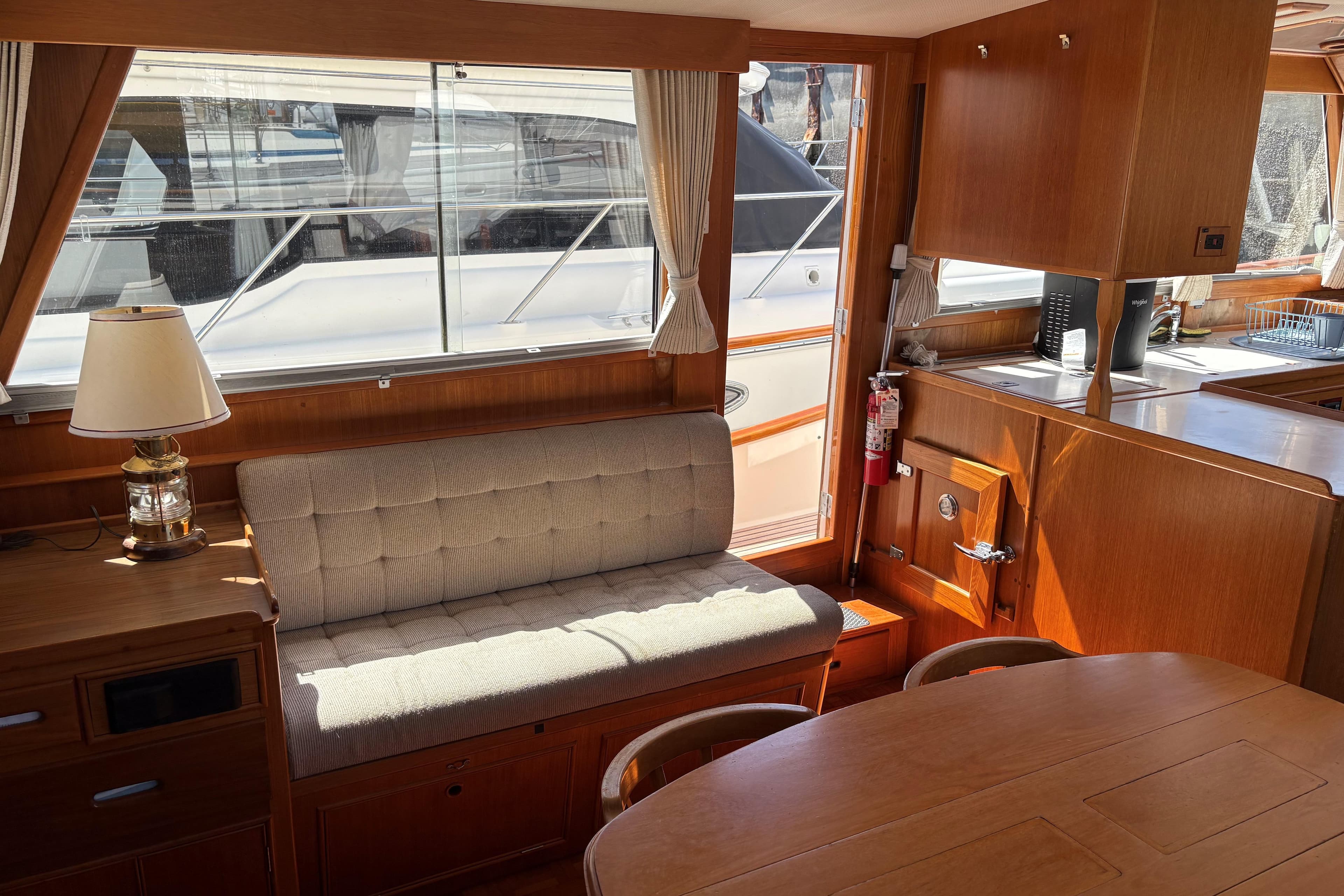 Interior of 1990 Grand Banks Classic yacht with wooden furnishings and cozy seating area.