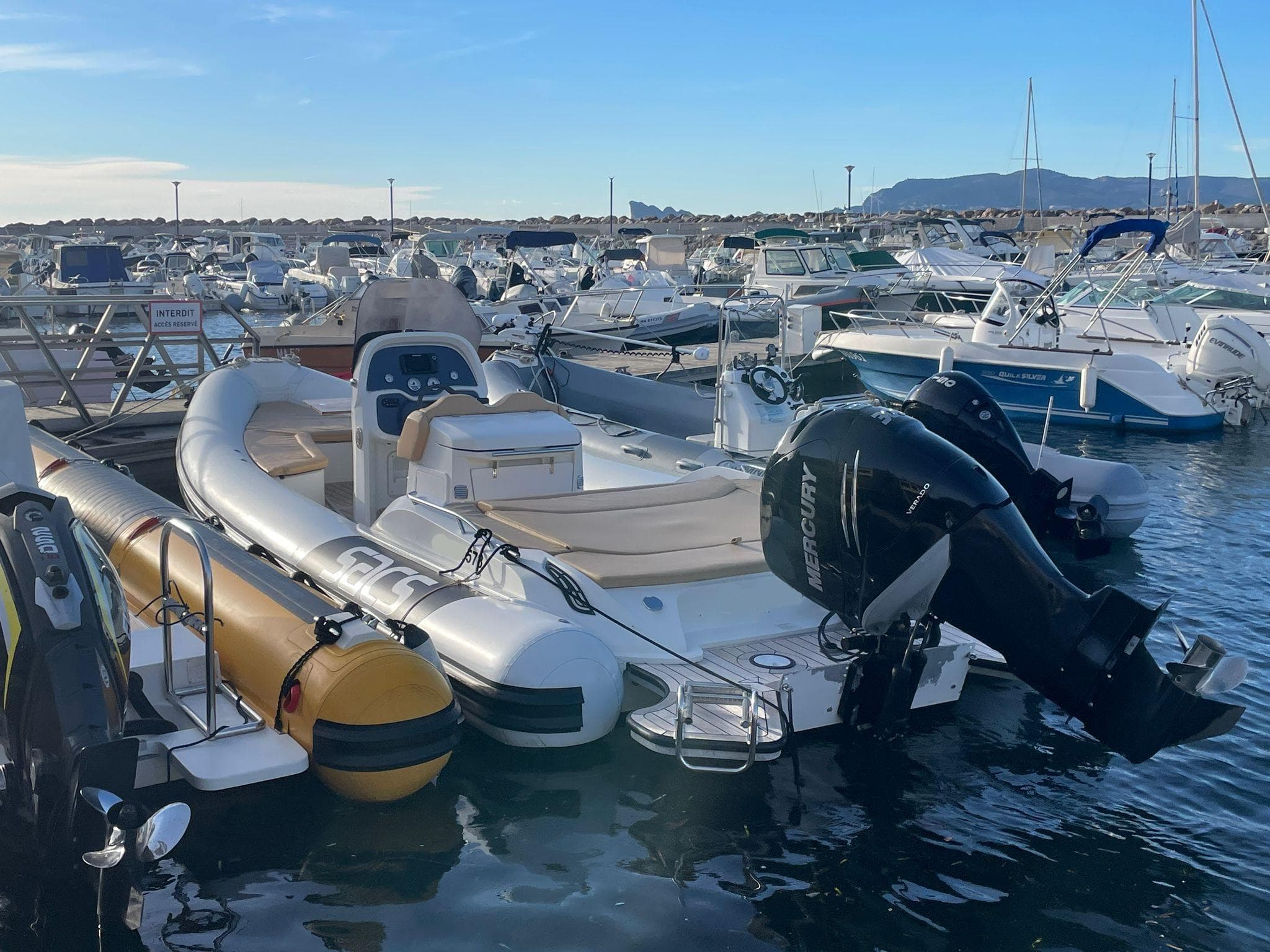 2016 SACS Strider 8 boat docked in a marina, surrounded by other vessels.