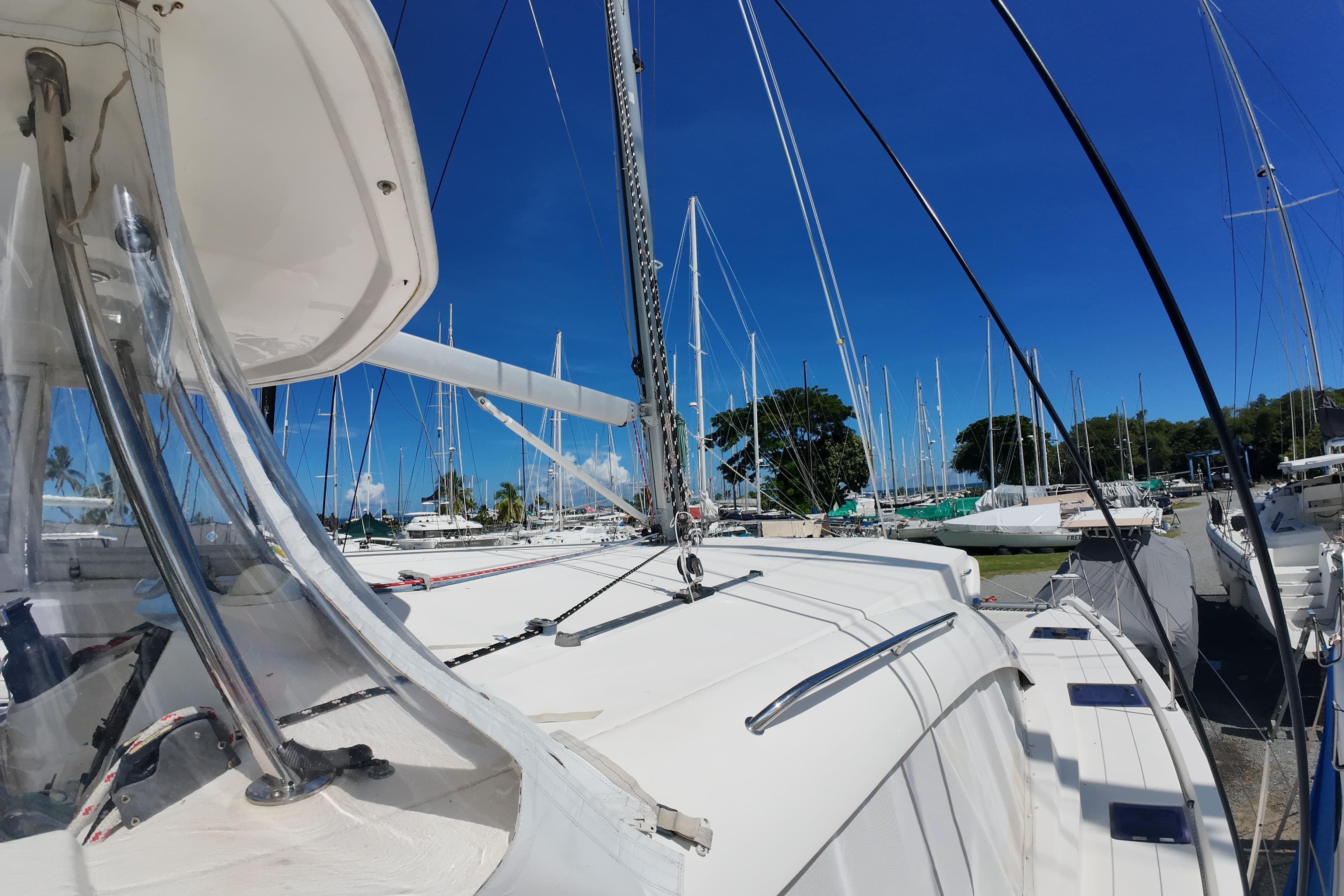 2015 Leopard 48 catamaran docked in a marina, surrounded by sailboats under a clear blue sky.