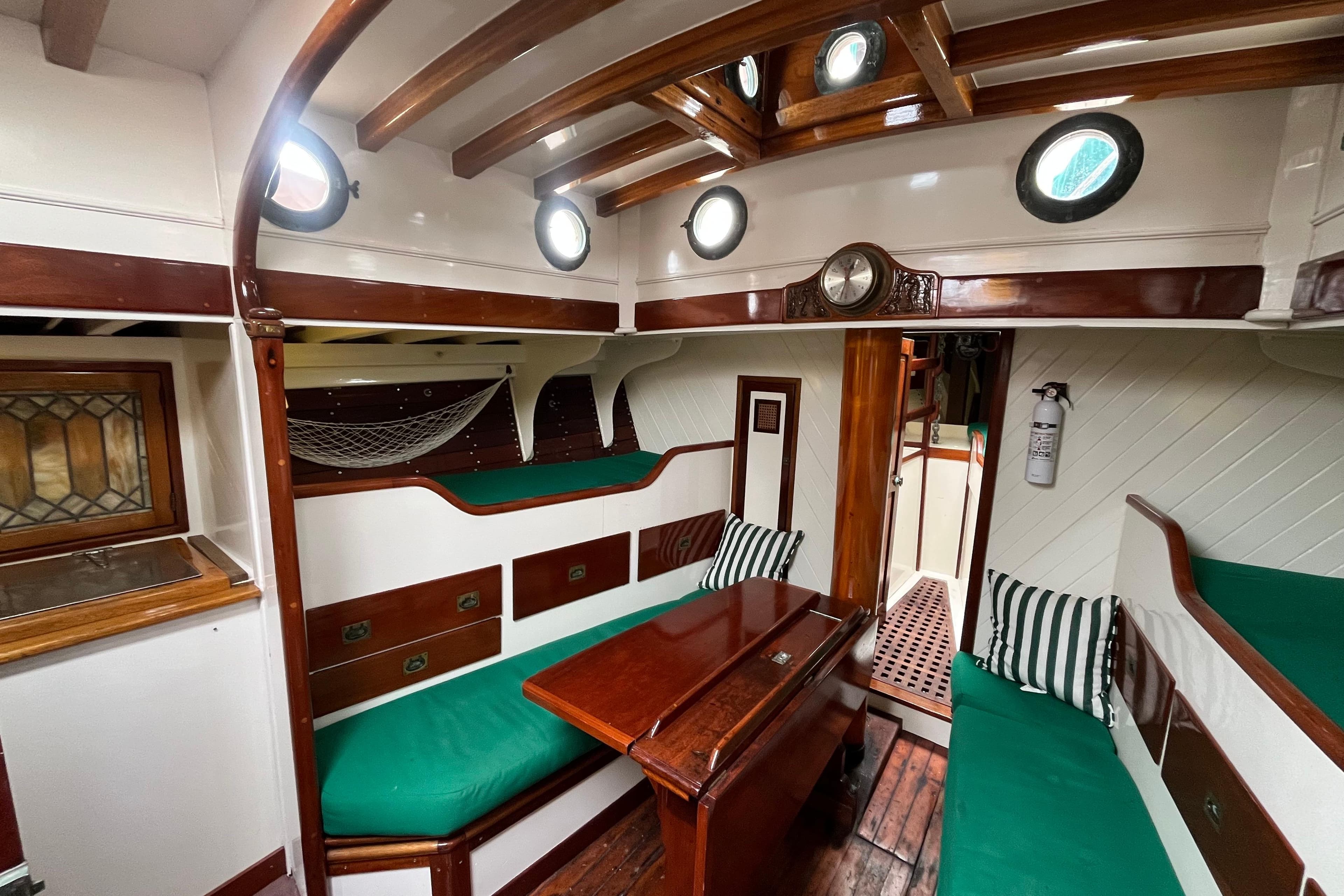 Interior of a 1947 Murray Peterson Schooner with green cushions and wooden accents.