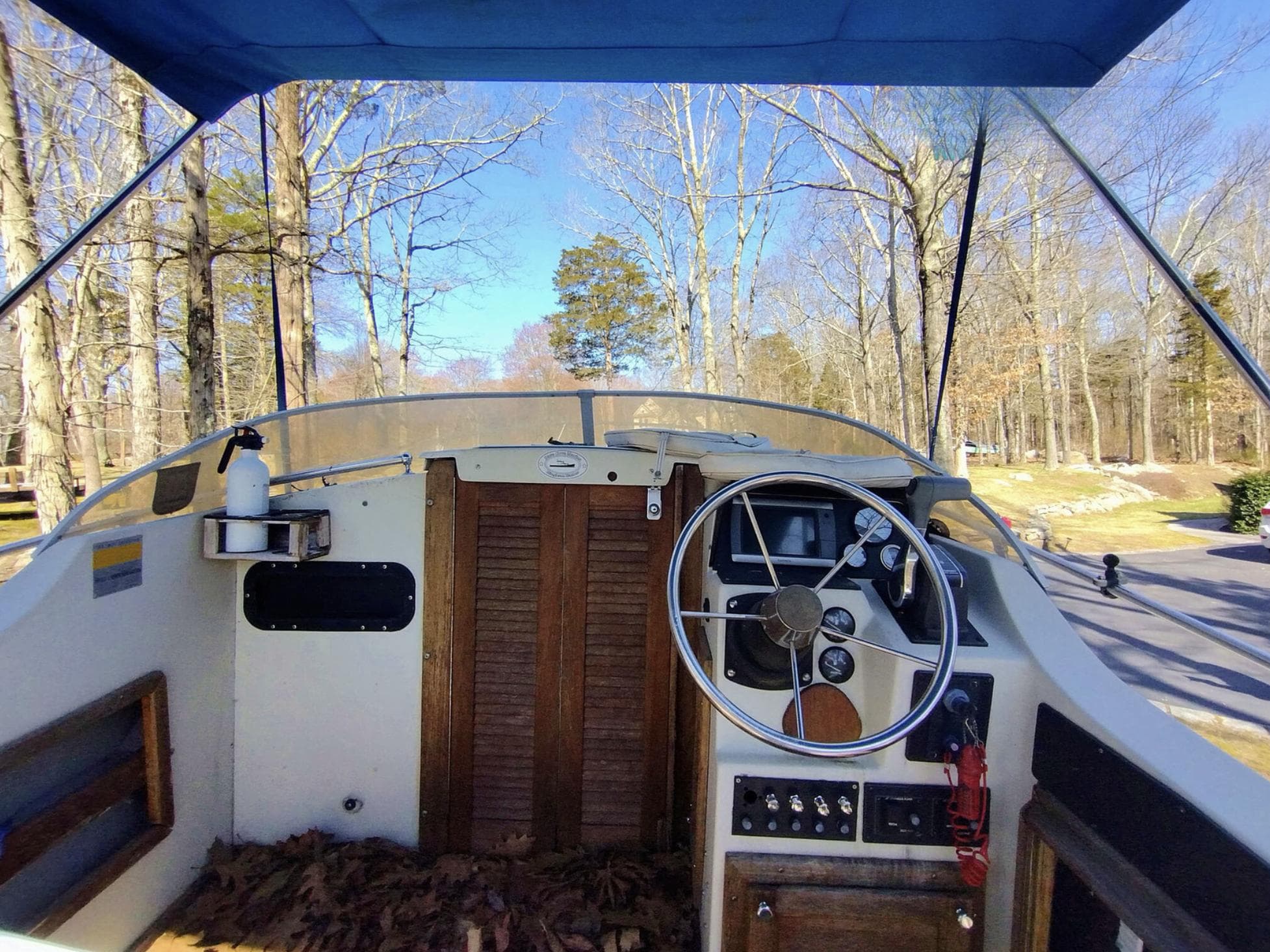 1983 Boston Whaler 25 Revenge boat cockpit with steering wheel, wooden doors, and outdoor setting.