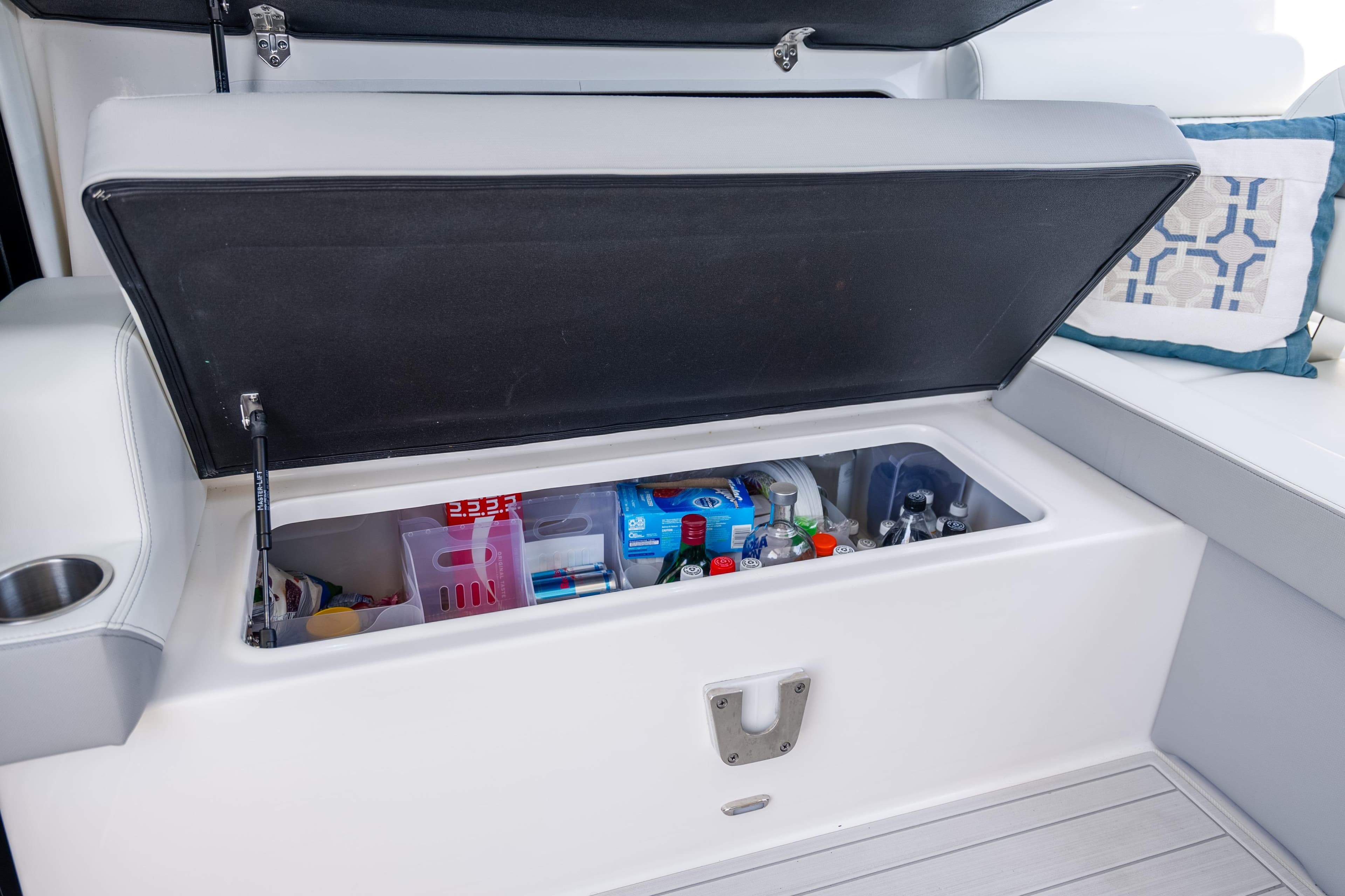 Open storage compartment on 2022 Regal 36 Grande Coupe, stocked with beverages and snacks.