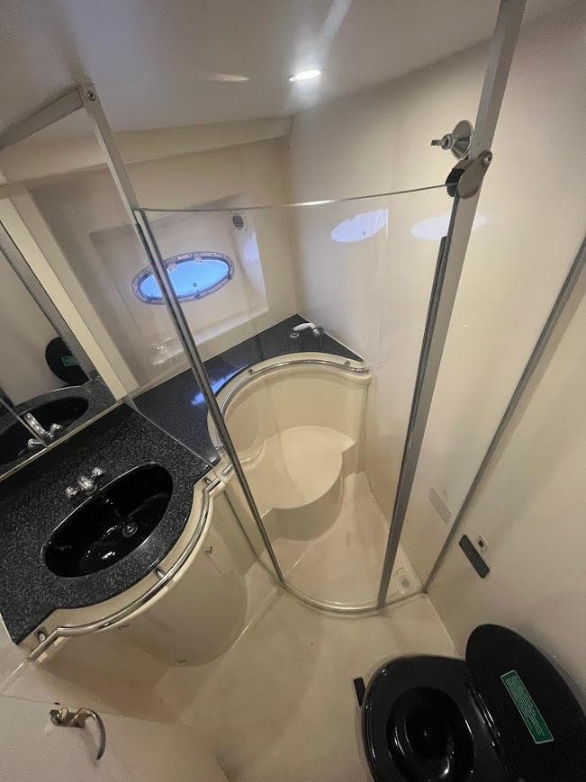 Bathroom interior of 2000 Carver 440 Hardtop Express yacht, featuring modern fixtures and porthole window.